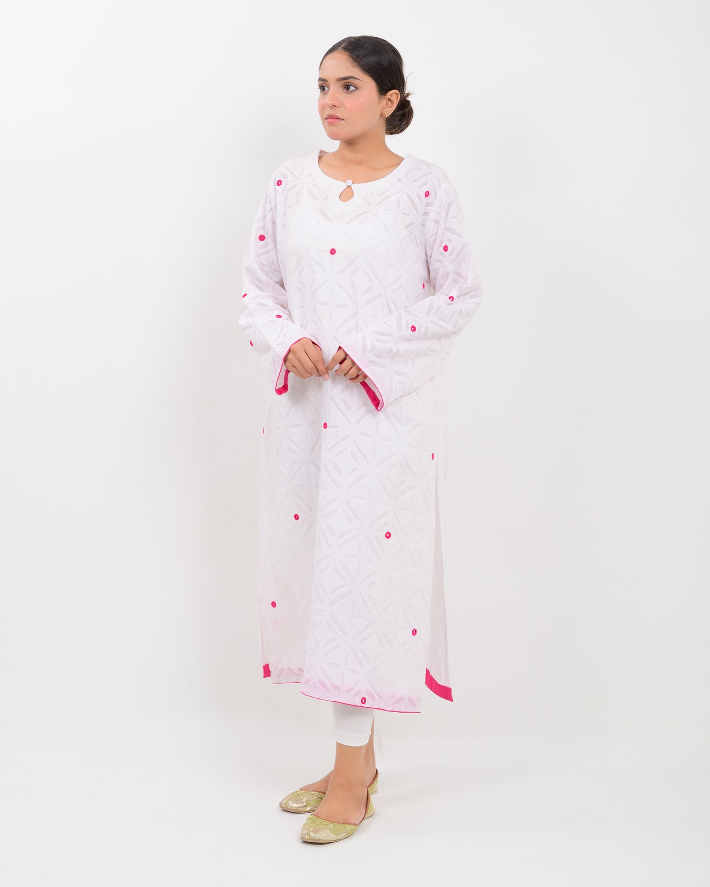 A woman wearing a white shirt with pink embroidery on a white background