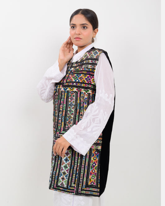 Woman wearing a colorful balochi embroidered vest over a white shirt on a white background