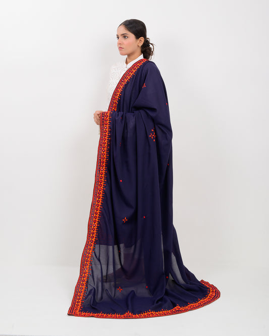 Woman wearing a navy blue shawl with orange embroidery on a white background