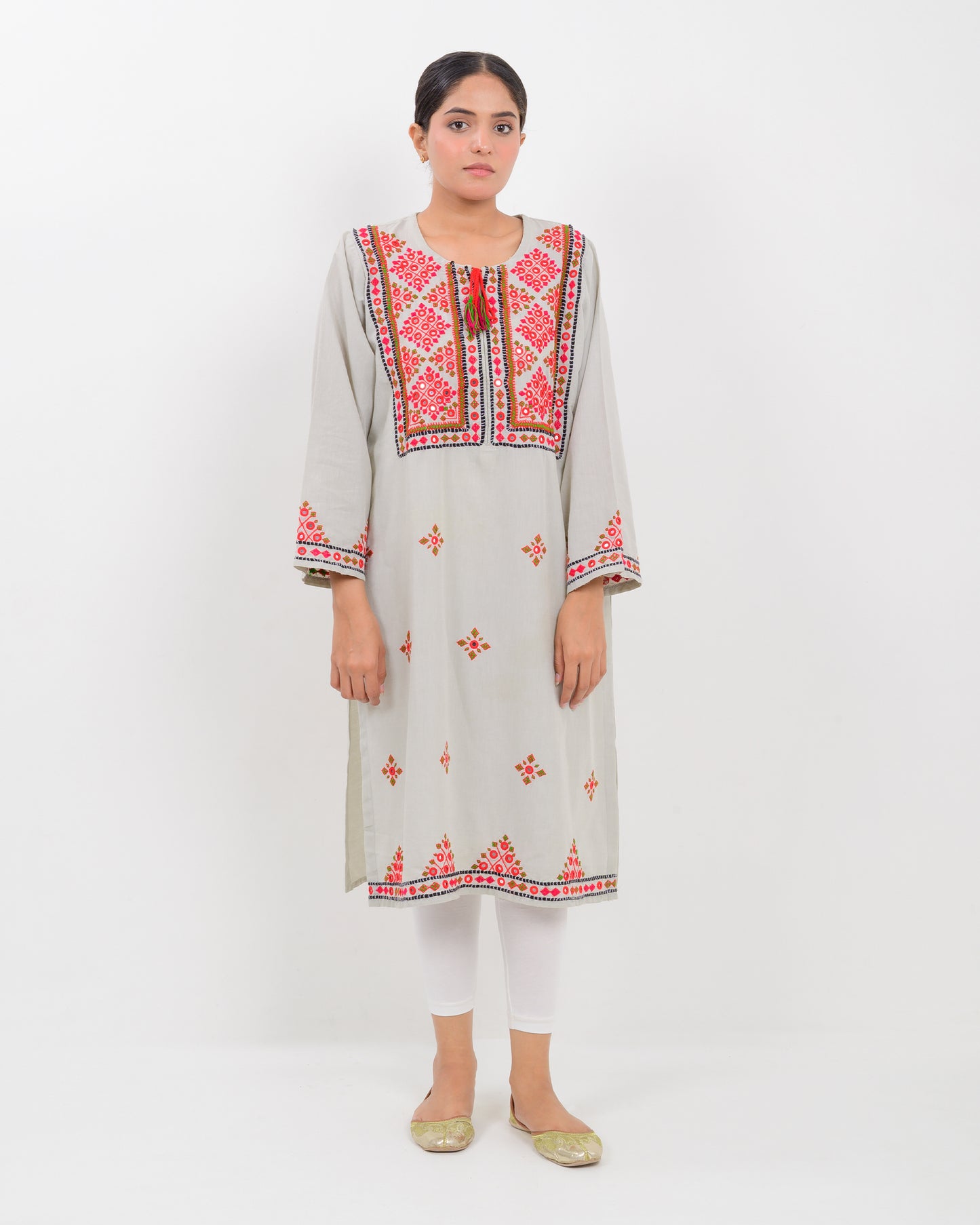 A woman wearing a light gray Balochi embroidery shirt on a white background