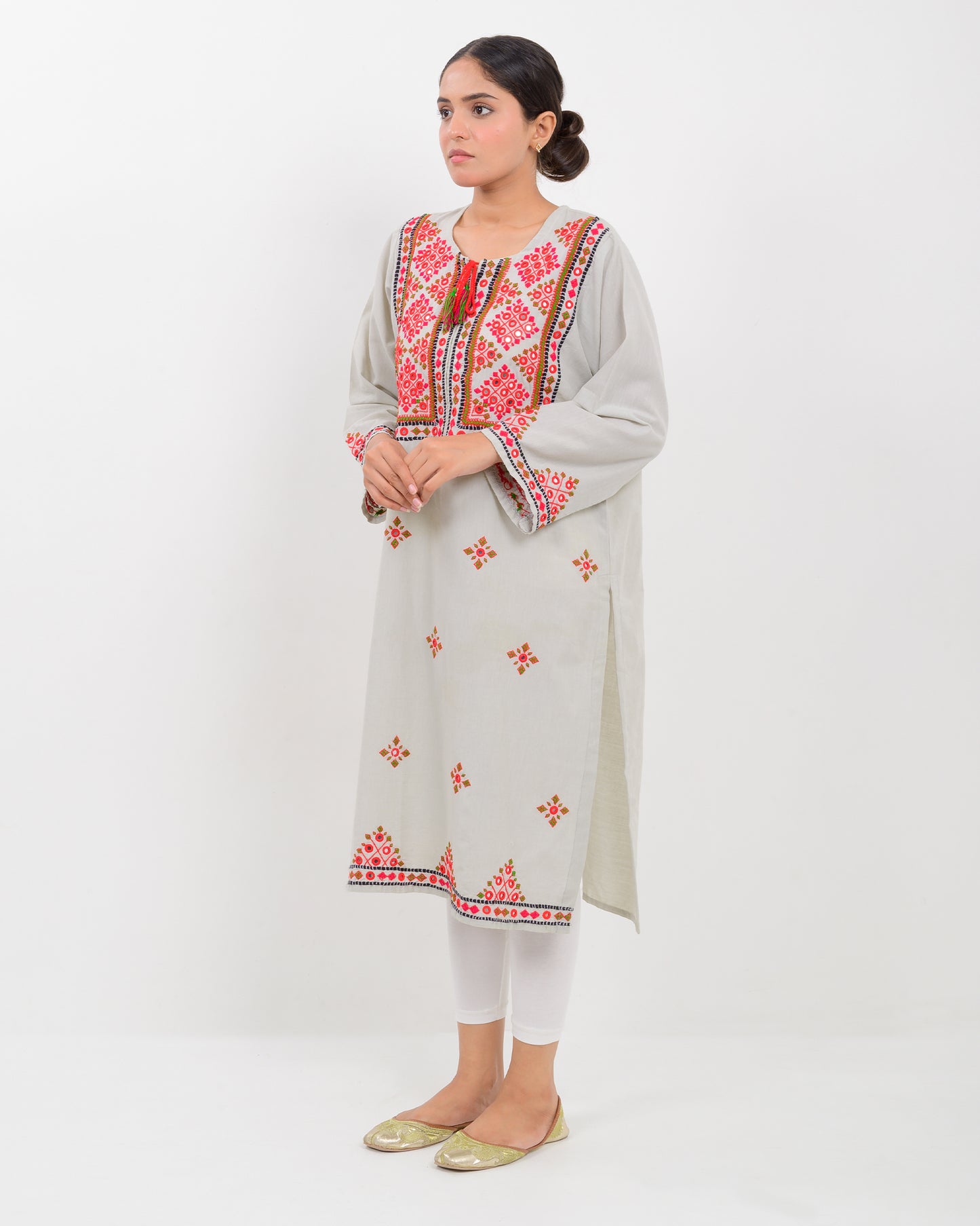 A woman wearing a light gray Balochi embroidery shirt on a white background