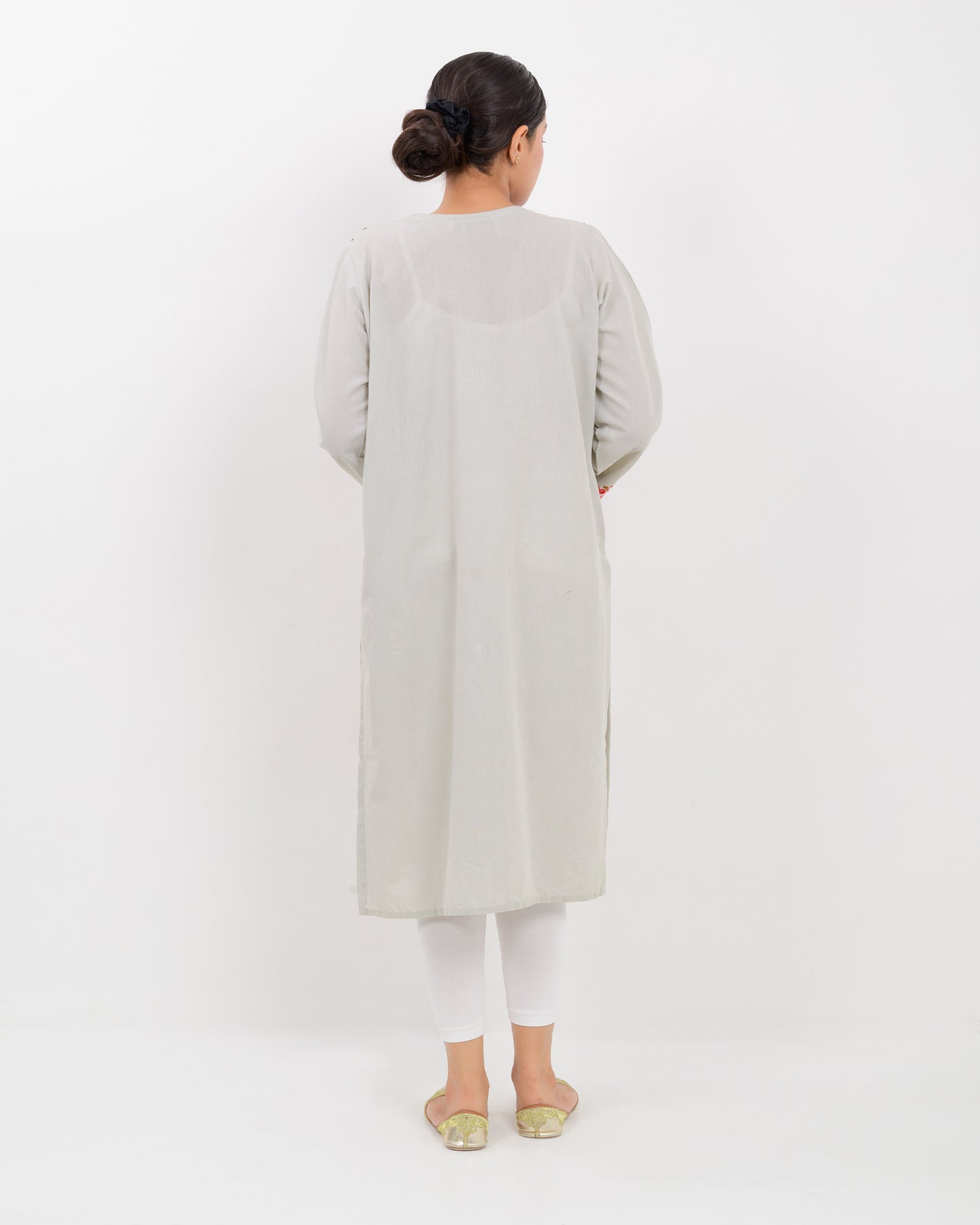 A woman wearing a light gray Balochi embroidery shirt on a white background