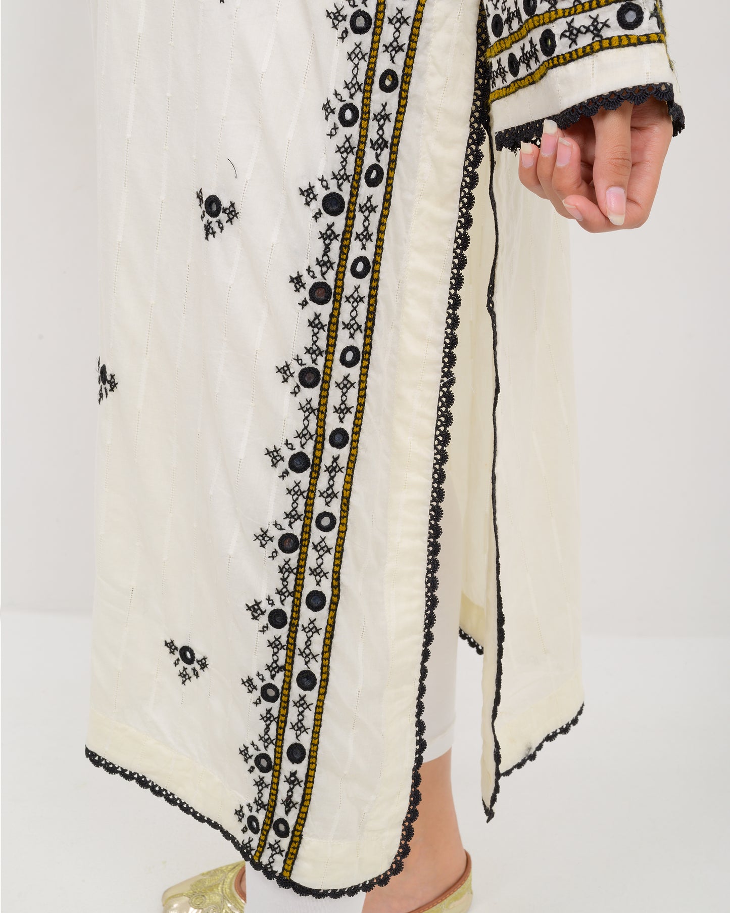 Woman wearing a white balochi embroidered kurta shirt with black patterns on a white background