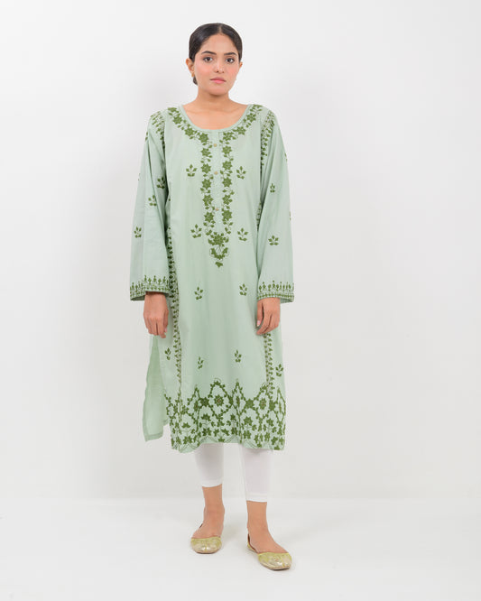 Woman wearing an Applique cutwork green embroidered Shirt with white pants on a white background