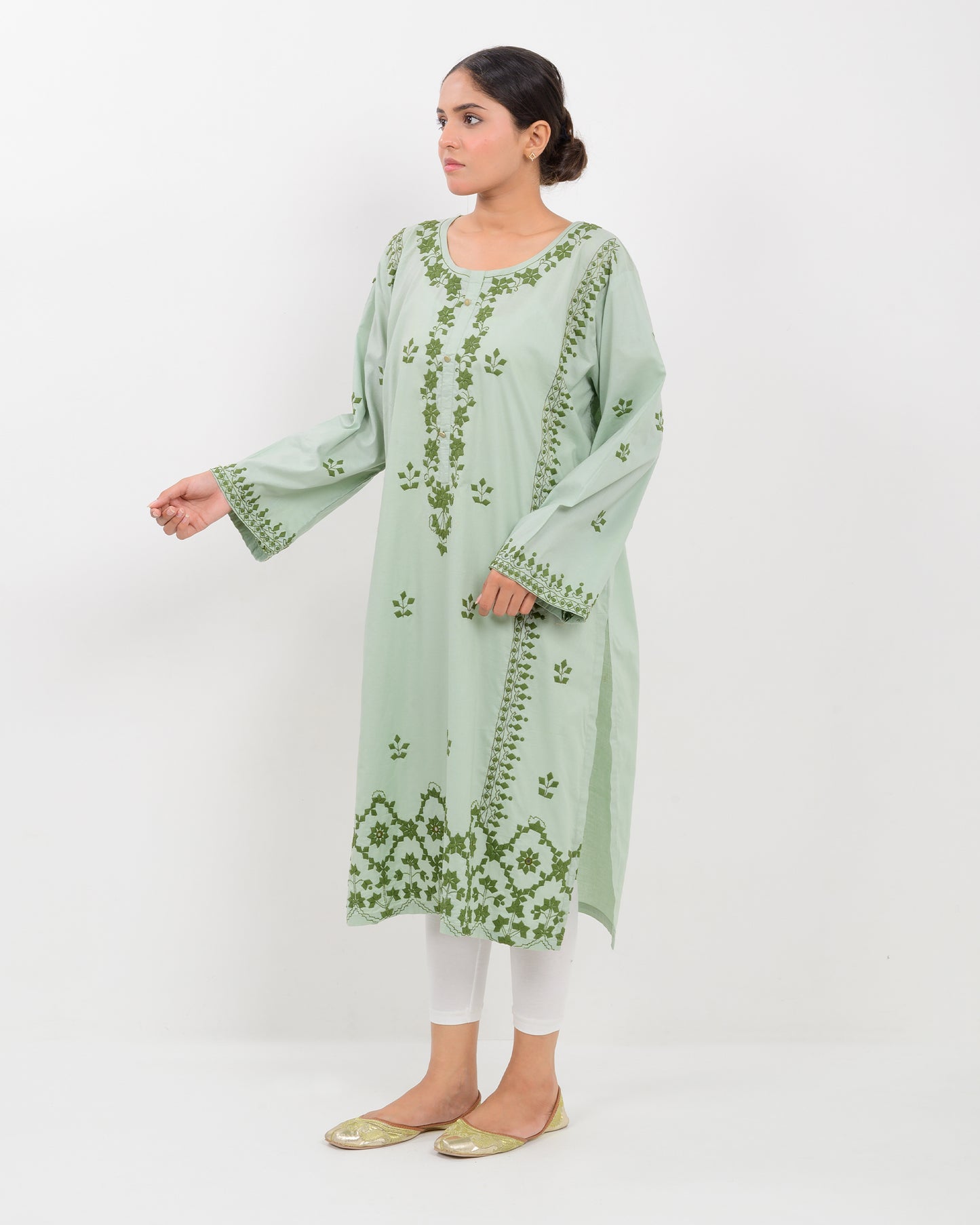 Woman wearing an Applique cutwork green embroidered Shirt with white pants on a white background