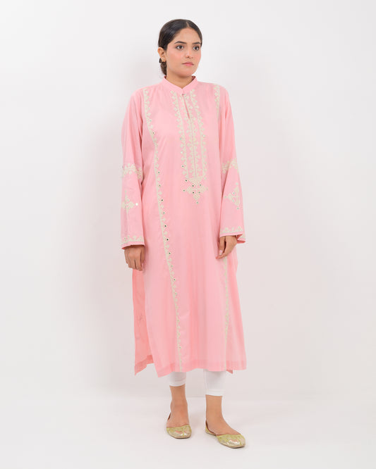 Woman wearing a pink cotton shirt with white embroidery on a white plan background