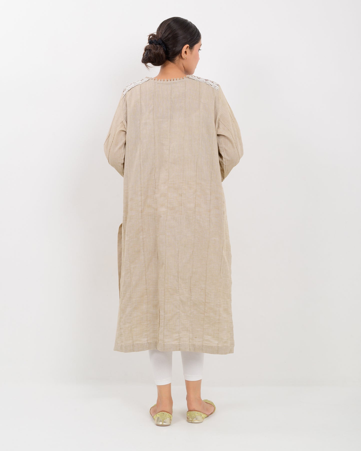 A woman wearing a kachi sui craft mirror work beige long shirt with white pants.