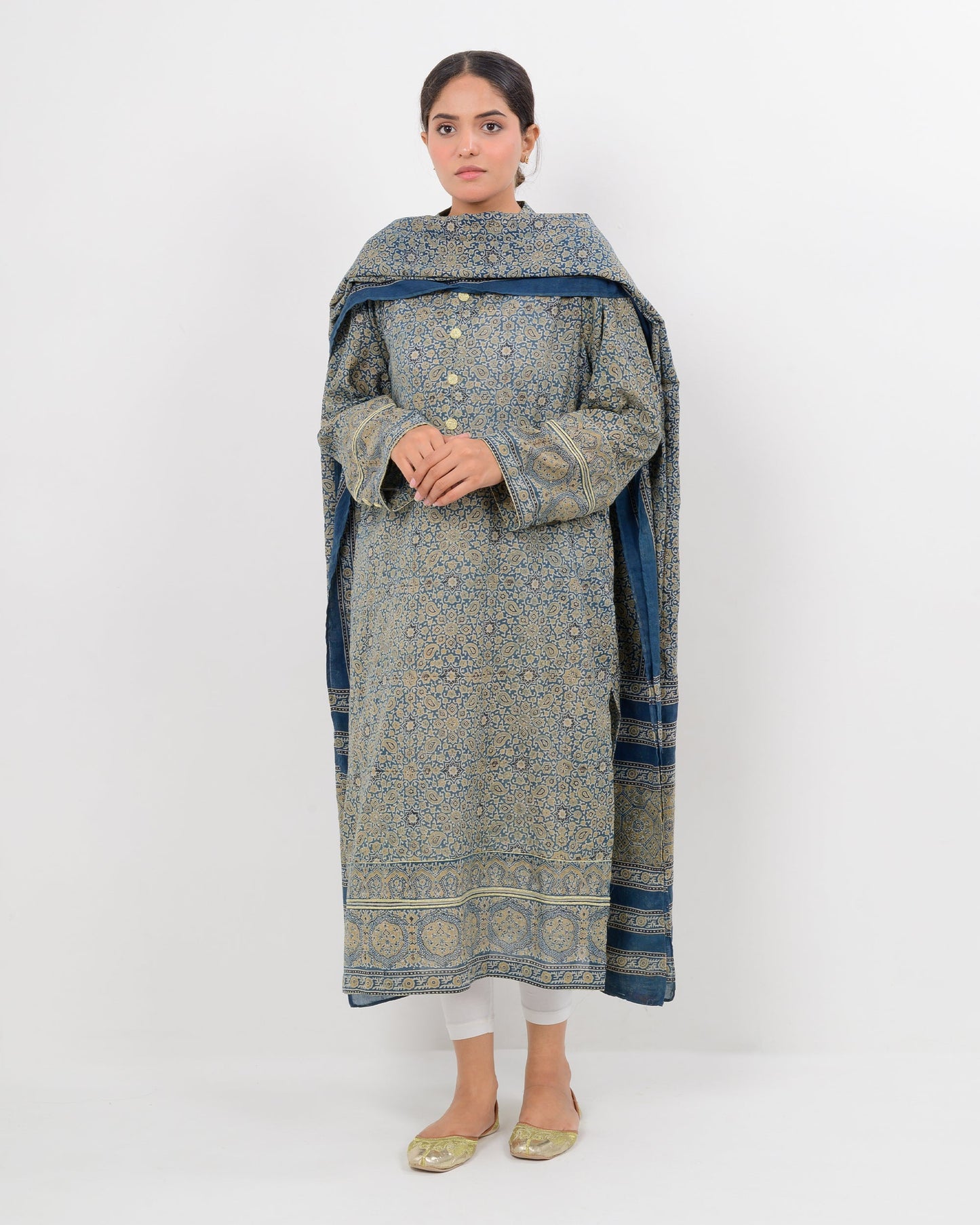 Woman wearing a long, patterned dress with a matching shawl on a white background