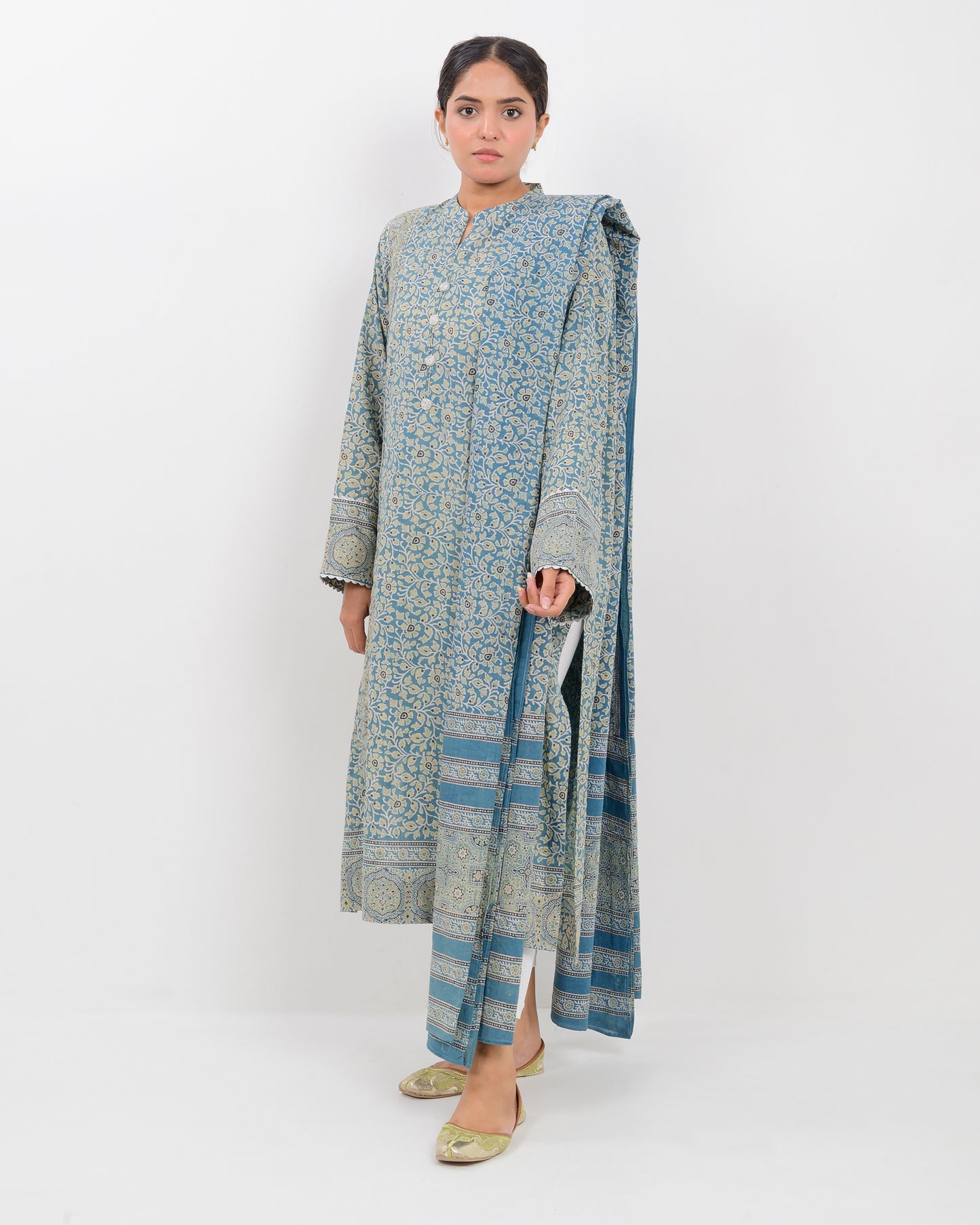 Woman wearing a long, patterned dress with a dupatta against a white background