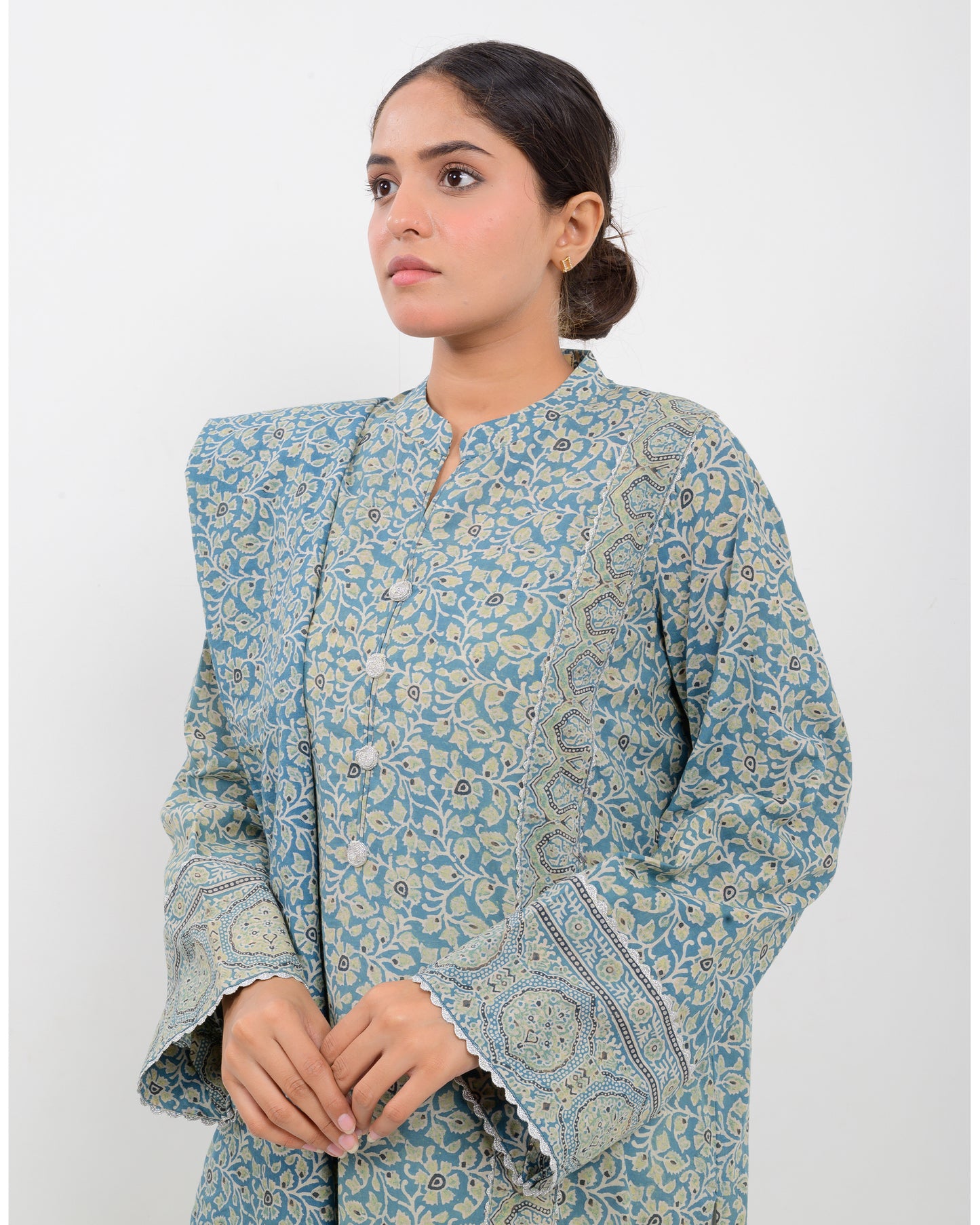 Woman wearing a long, patterned dress with a dupatta against a white background