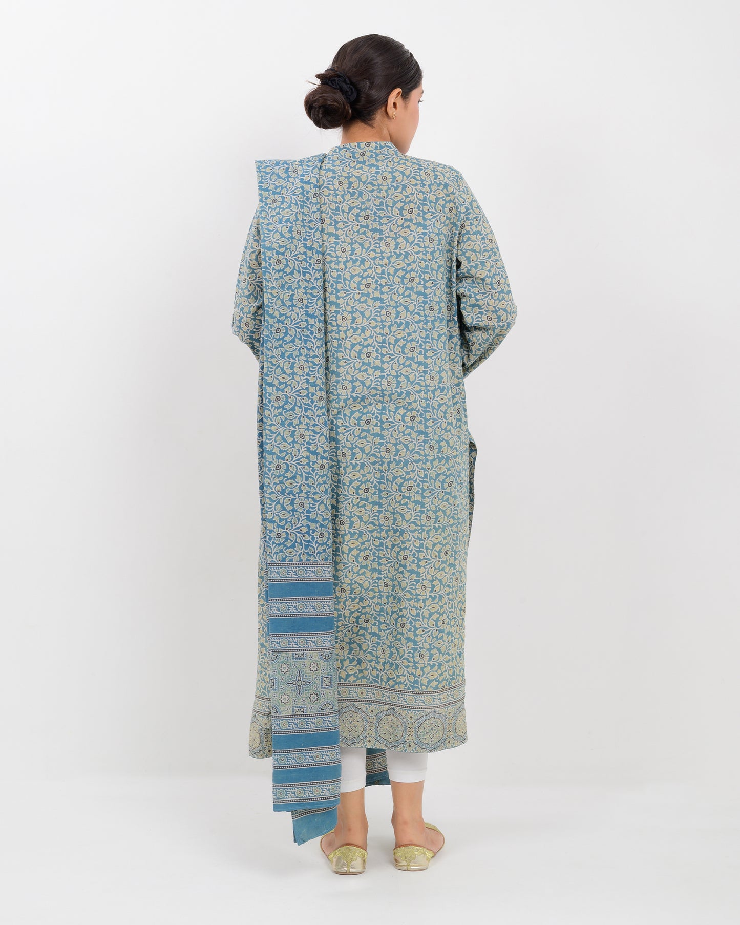 Woman wearing a long, patterned dress with a dupatta against a white background