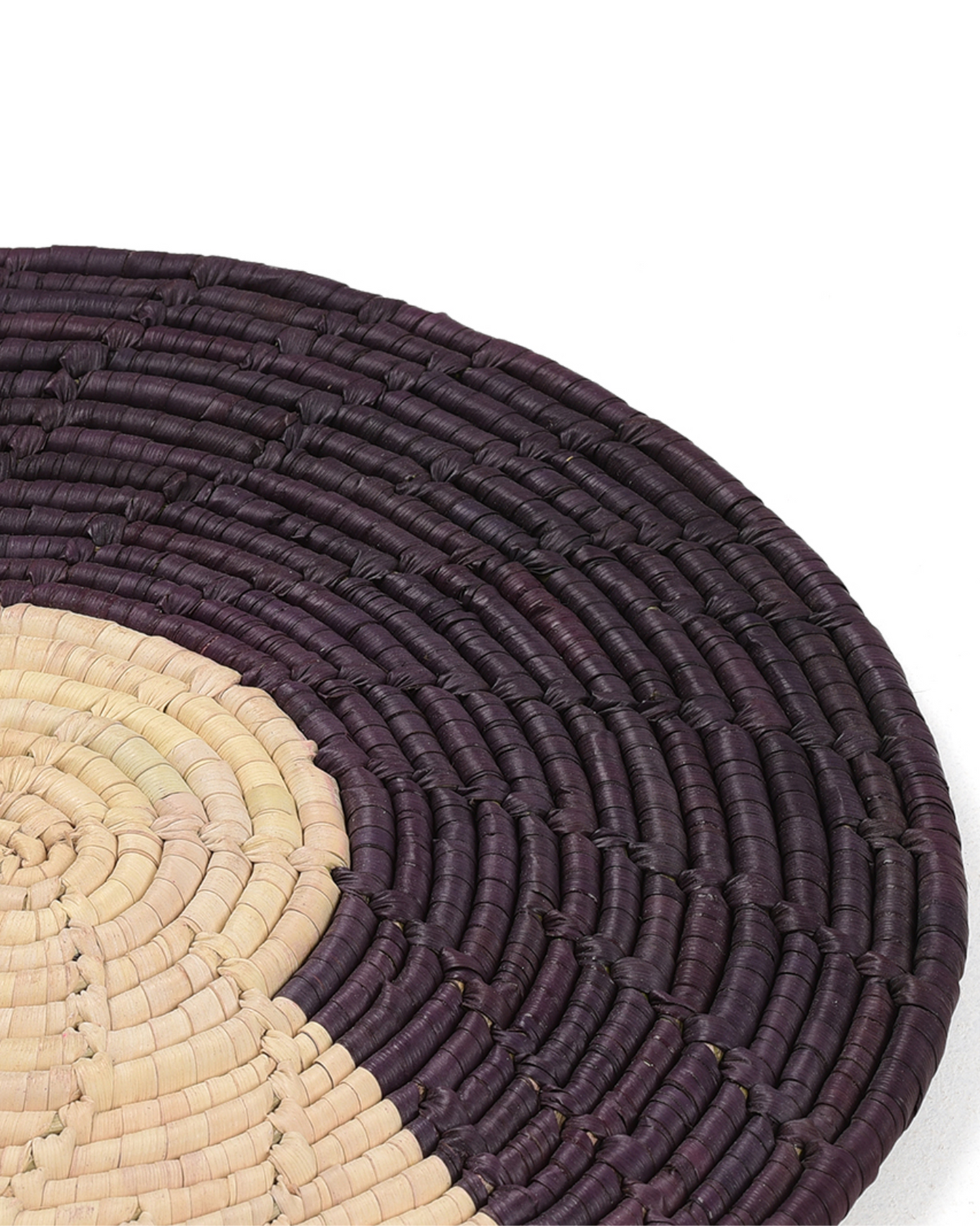 Close-up of a woven placemat with concentric circle pattern on a white background