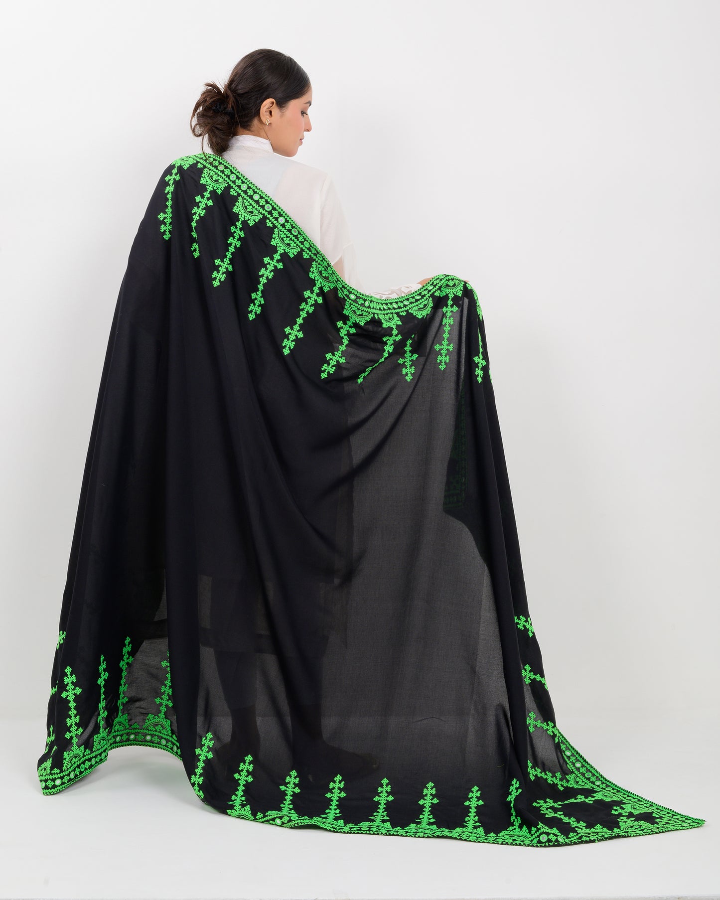 Woman wearing a black color with green hurmich embroidery shawl on a white background
