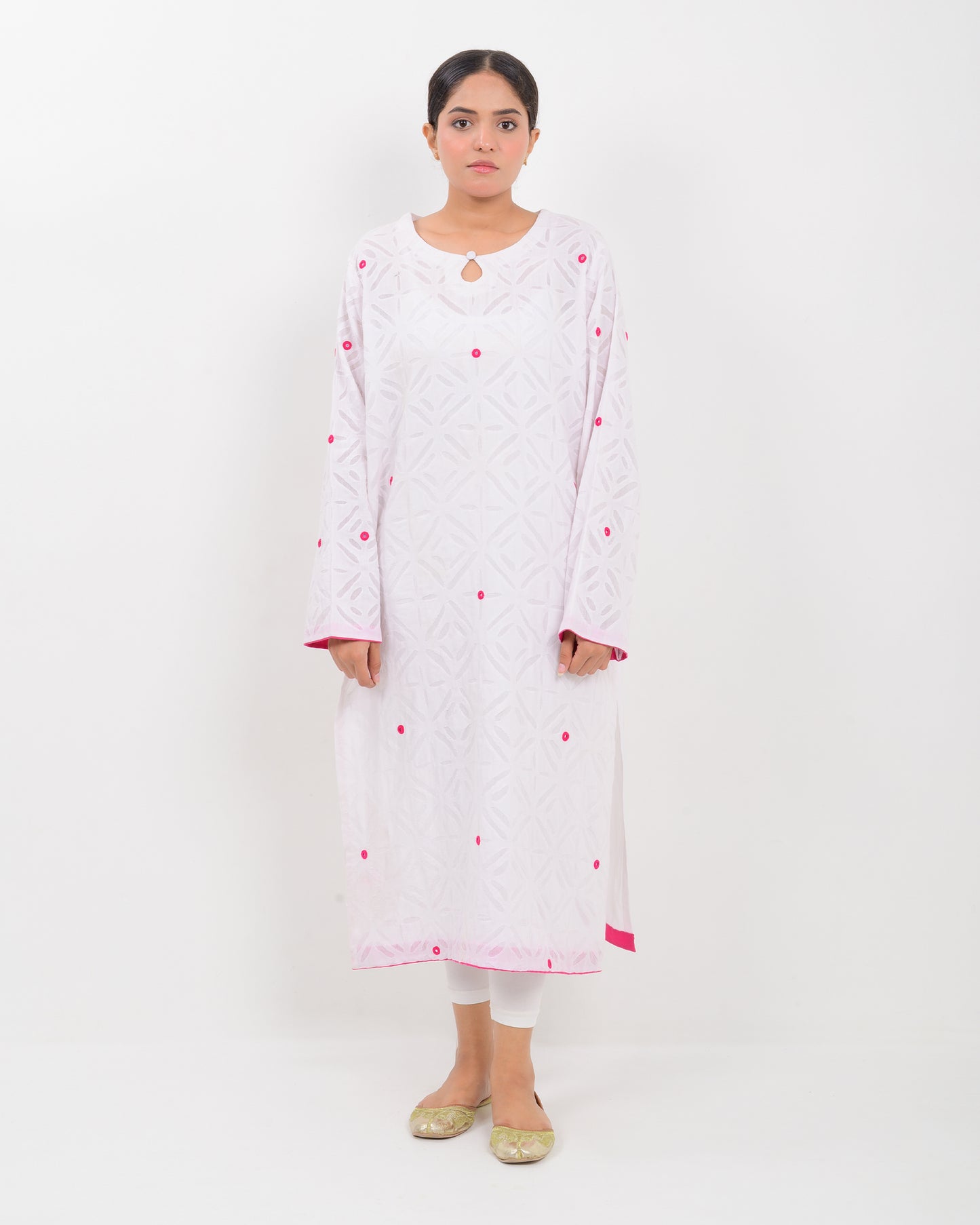 A woman wearing a white shirt with pink embroidery on a white background