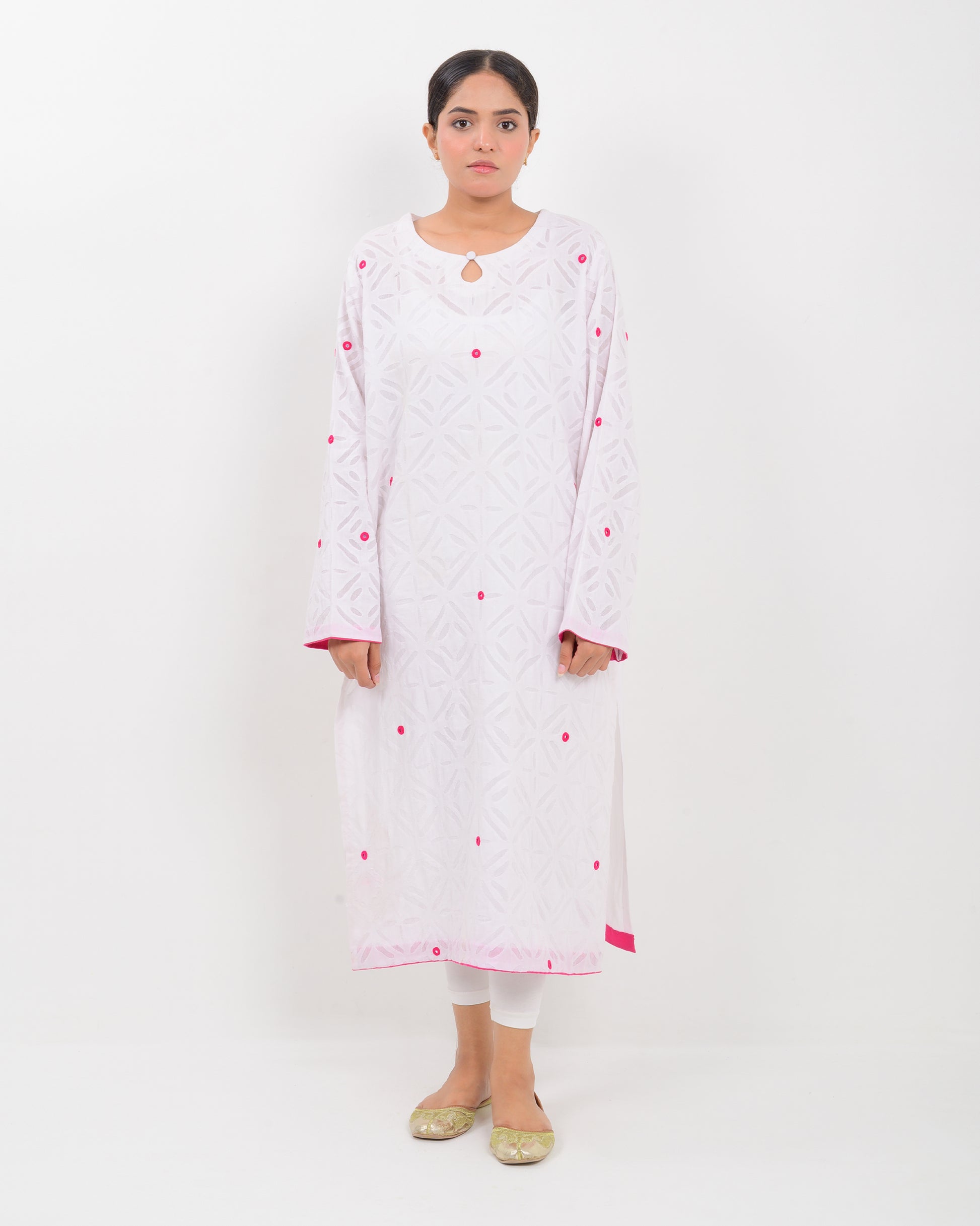 A woman wearing a white shirt with pink embroidery on a white background