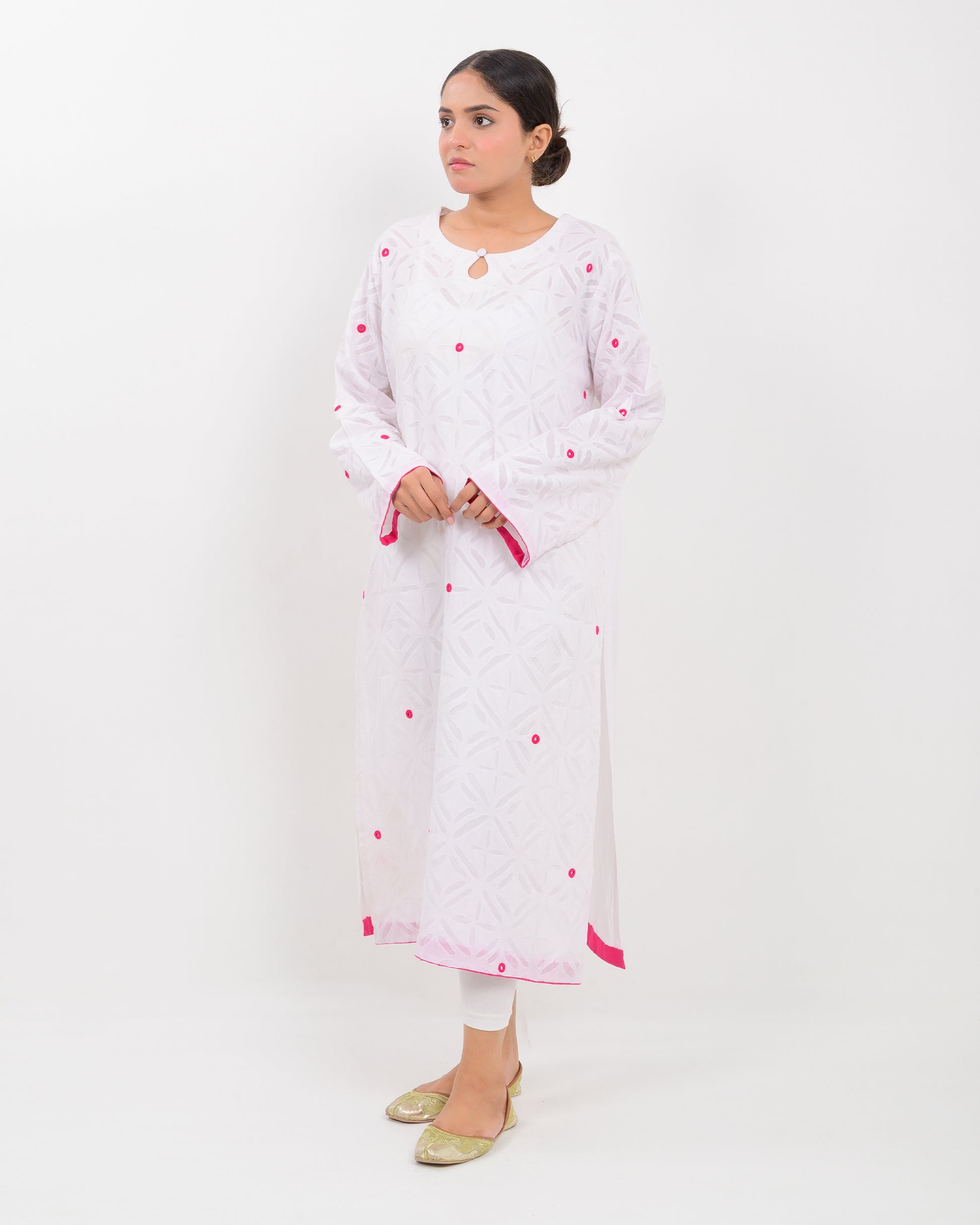 A woman wearing a white shirt with pink embroidery on a white background
