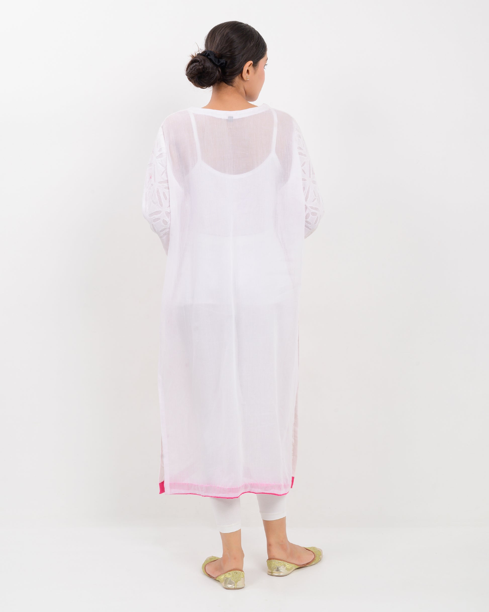 A woman wearing a white shirt with pink embroidery on a white background