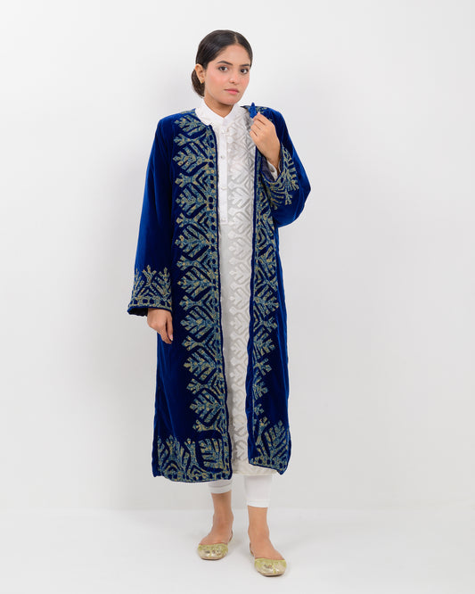 Woman wearing a blue applique cutwork velvet long overcoat outfit on a white background