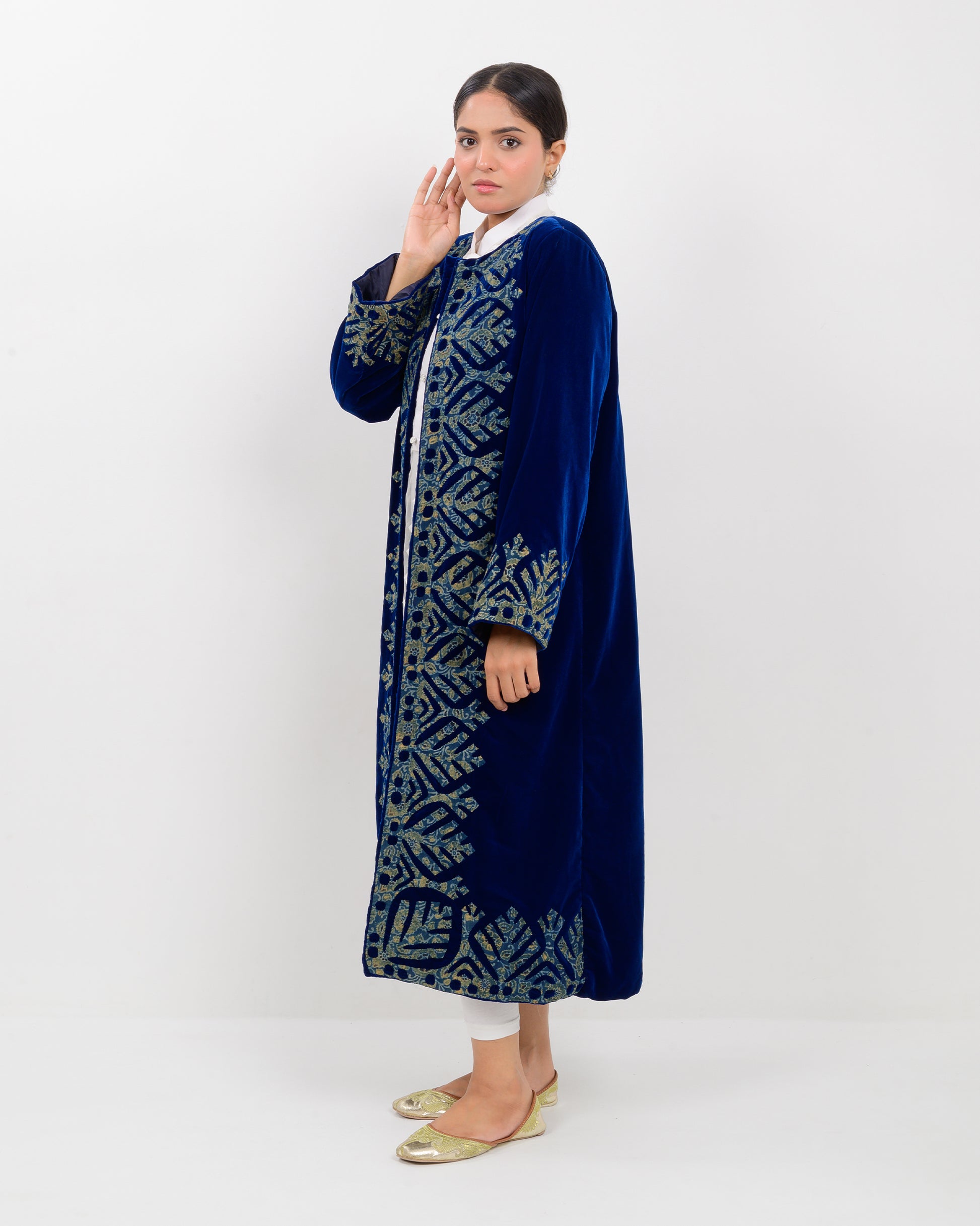 Woman wearing a blue applique cutwork velvet long overcoat outfit on a white background
