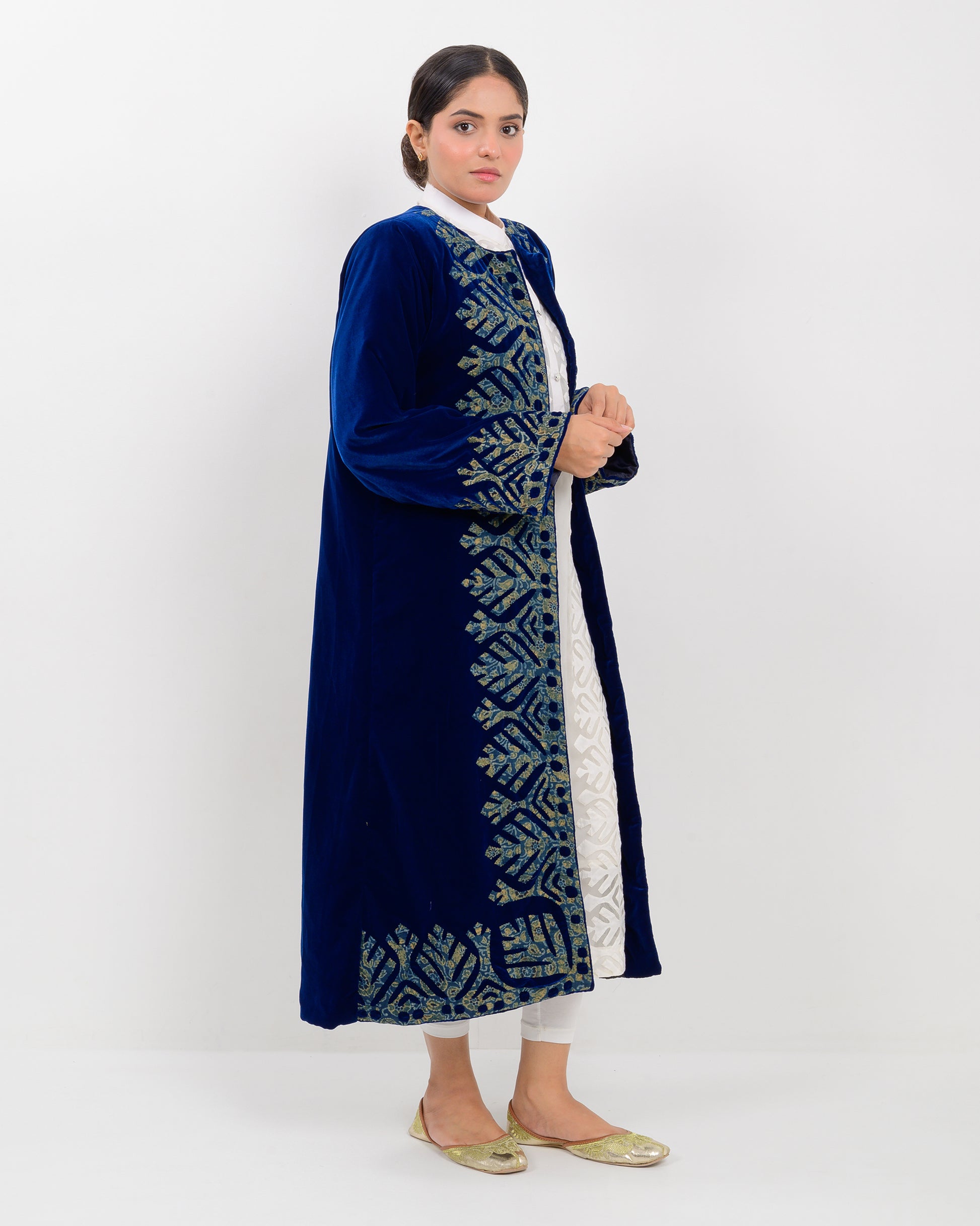 Woman wearing a blue applique cutwork velvet long overcoat outfit on a white background