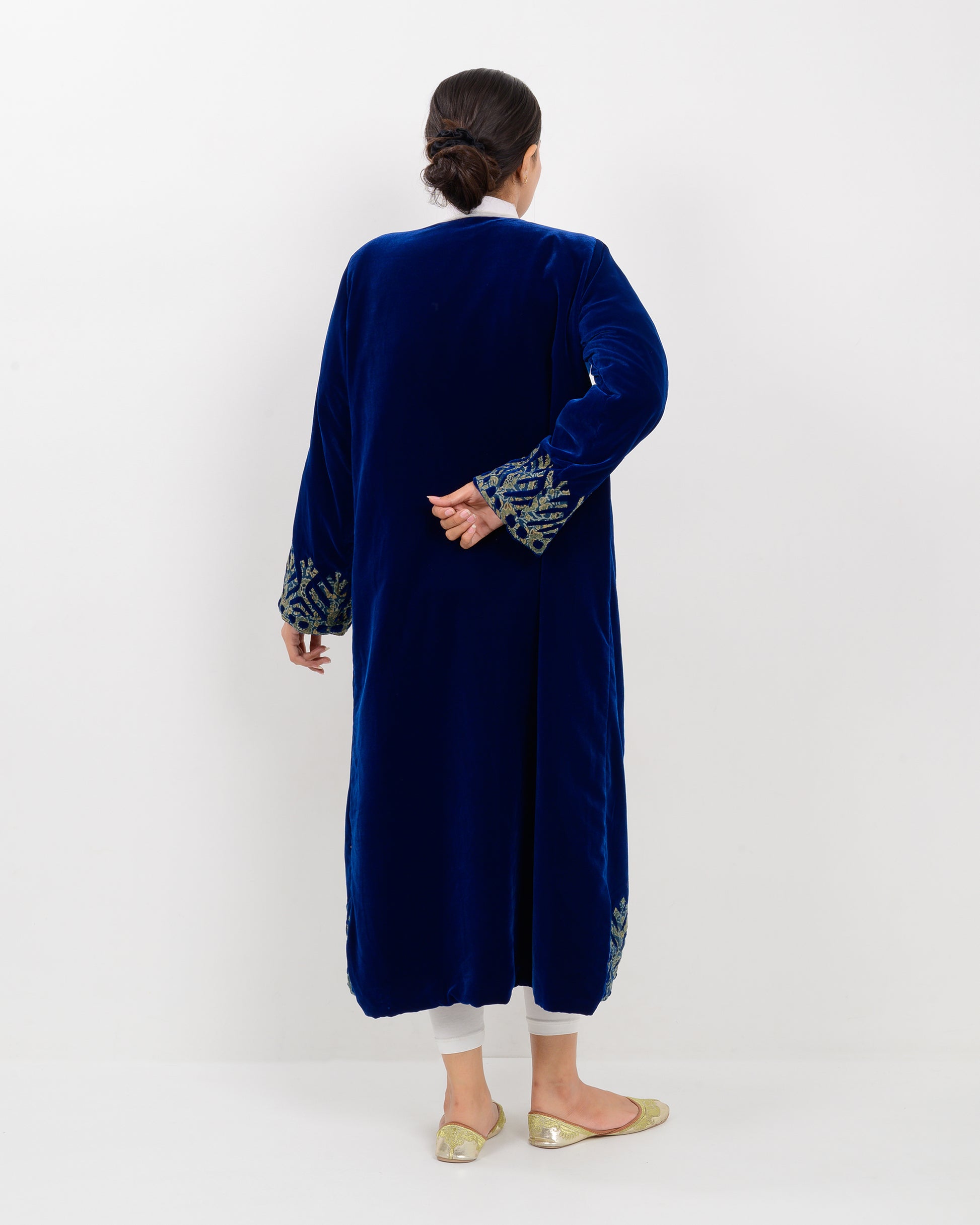 Woman wearing a blue applique cutwork velvet long overcoat outfit on a white background