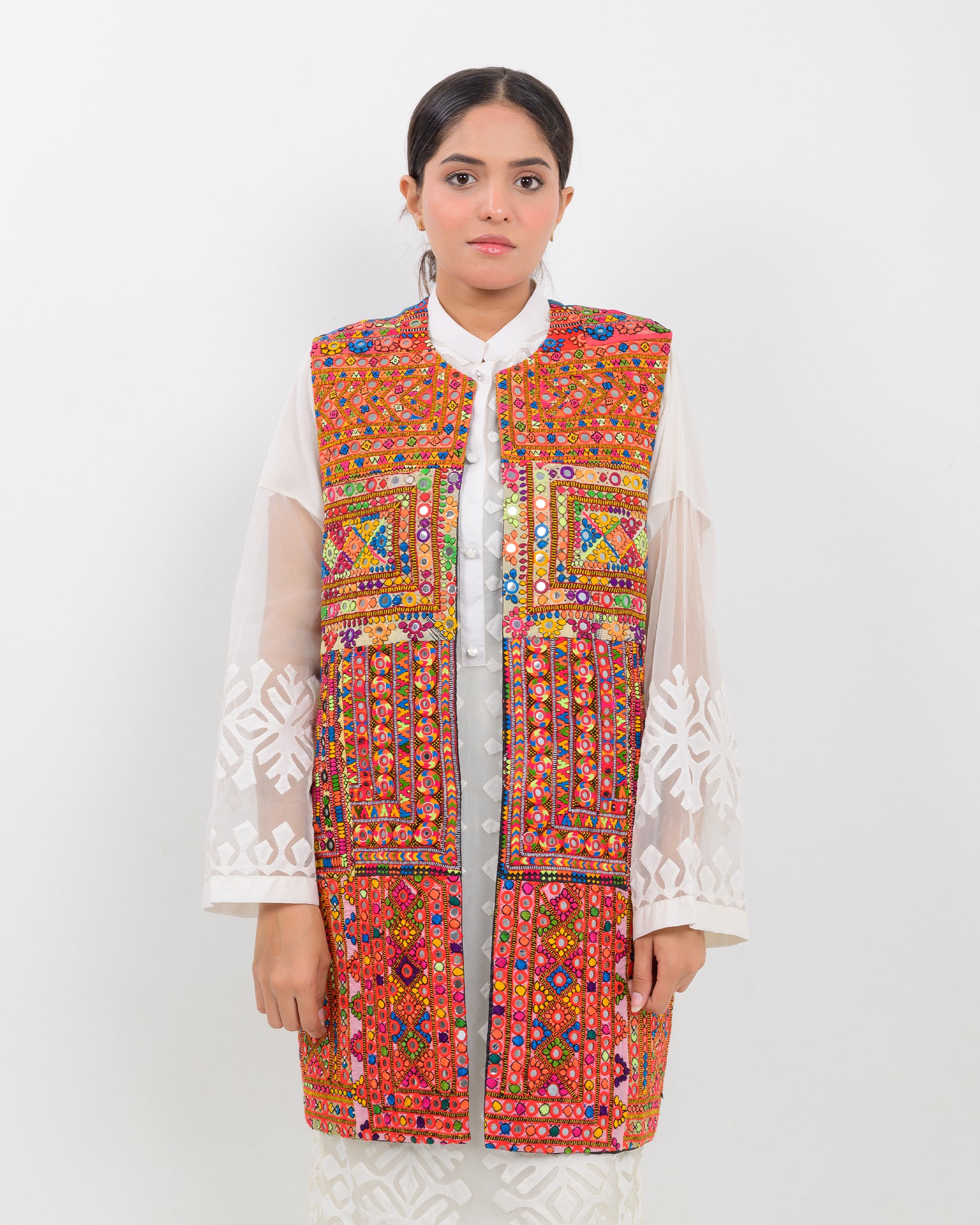 Woman wearing a colorful balochi embroidered vest on a white background