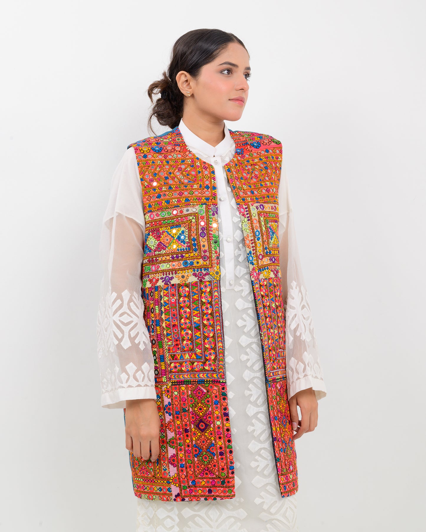 Woman wearing a colorful balochi embroidered vest on a white background