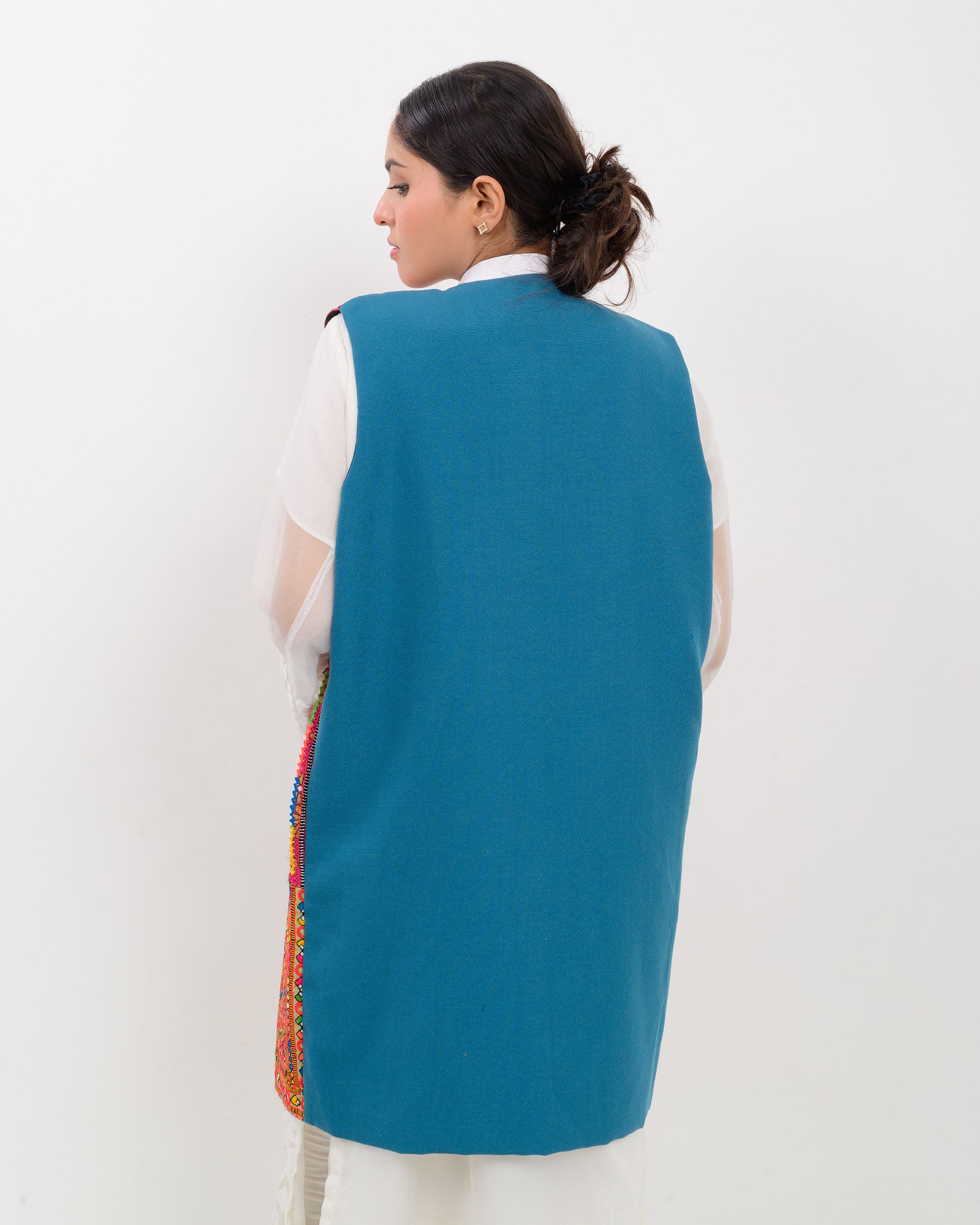 Woman wearing a colorful balochi embroidered vest on a white background