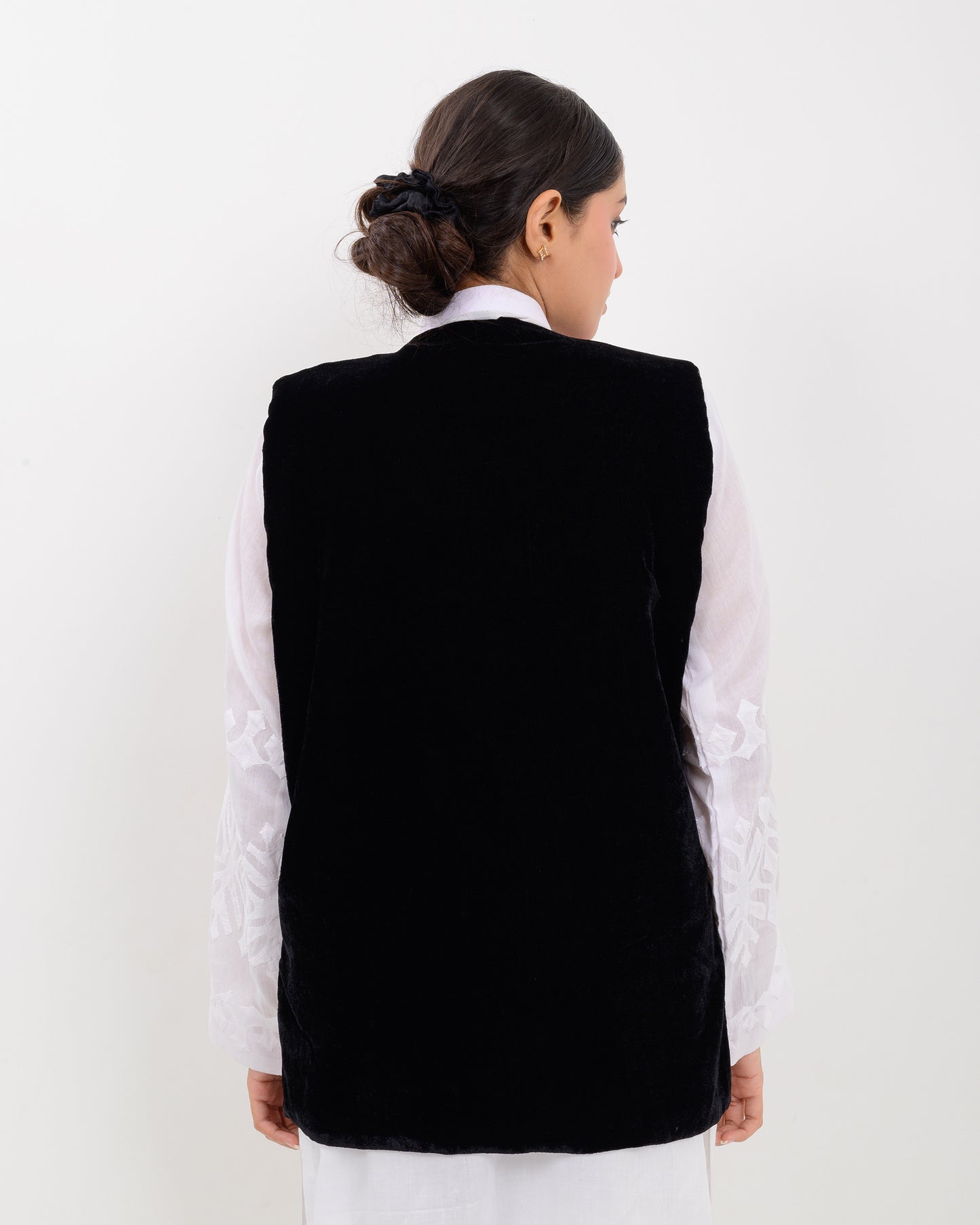 Woman wearing a colorful patterned Balochi embroidery vest over a white shirt on a white background