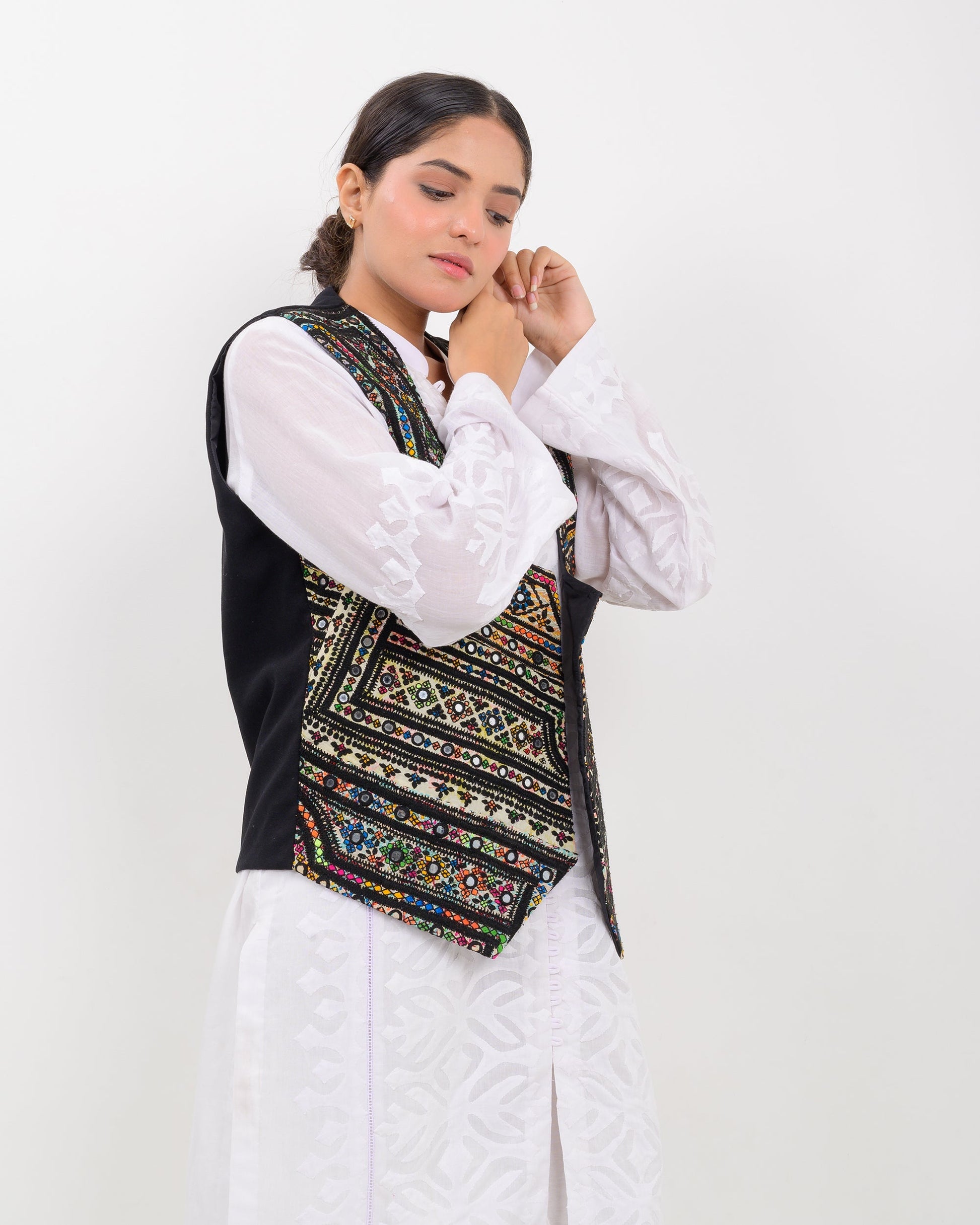 Woman wearing a traditional balochi embroidered vest over a white shirt on a white background