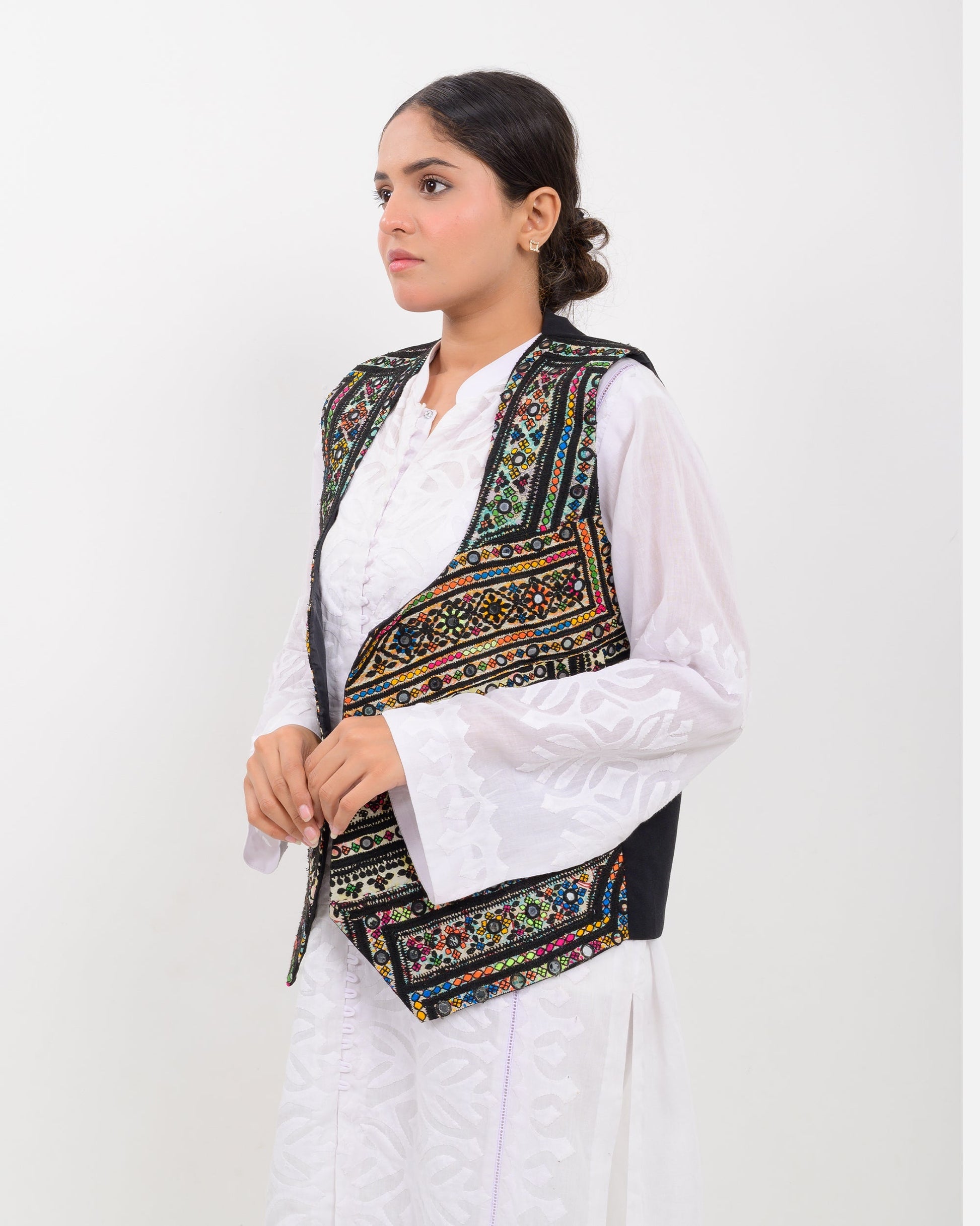 Woman wearing a traditional balochi embroidered vest over a white shirt on a white background