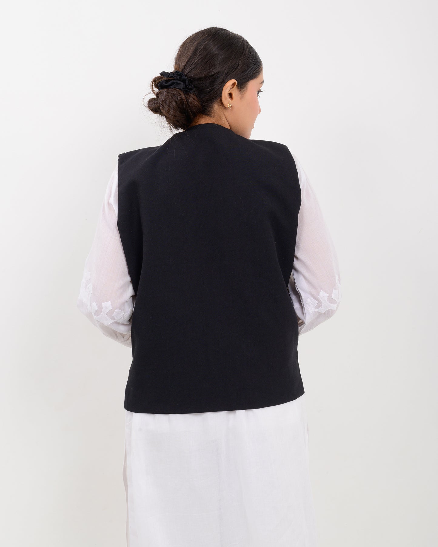 Woman wearing a traditional balochi embroidered vest over a white shirt on a white background