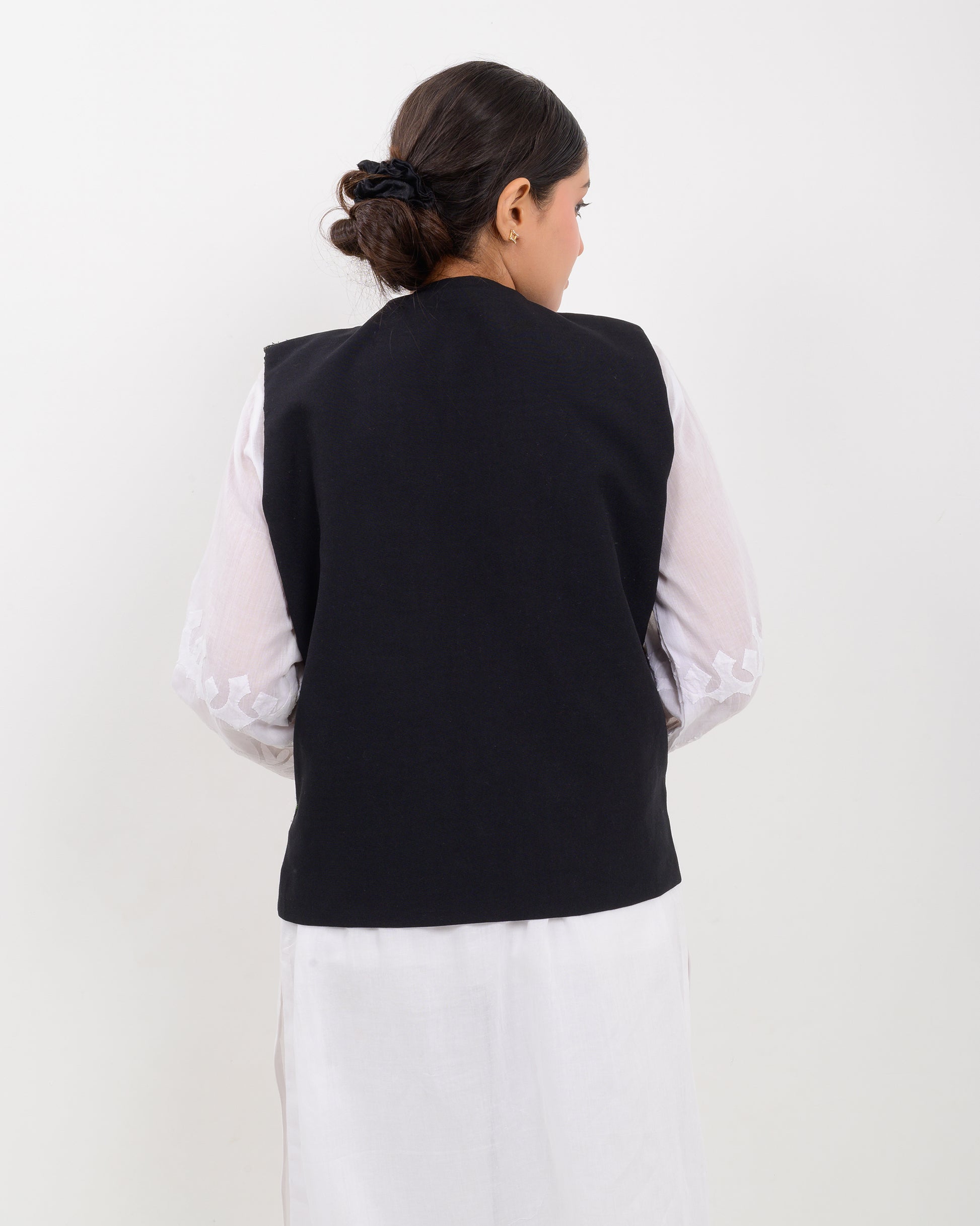 Woman wearing a traditional balochi embroidered vest over a white shirt on a white background