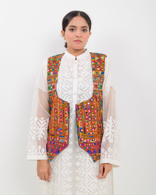 Woman wearing a colorful patterned Balochi embroidery vest over a white outfit on a white background