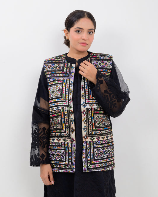 A woman wearing a colorful Balochi embroidered vest with sheer sleeves on a white background