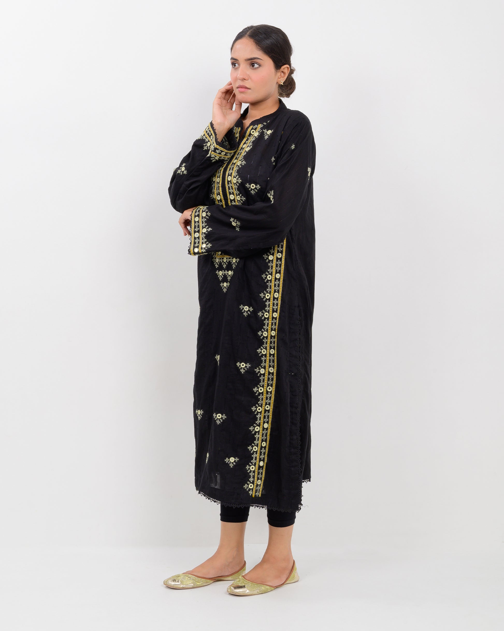 Woman wearing a black balochi embroidered kurta shirt with yellow patterns on a white background