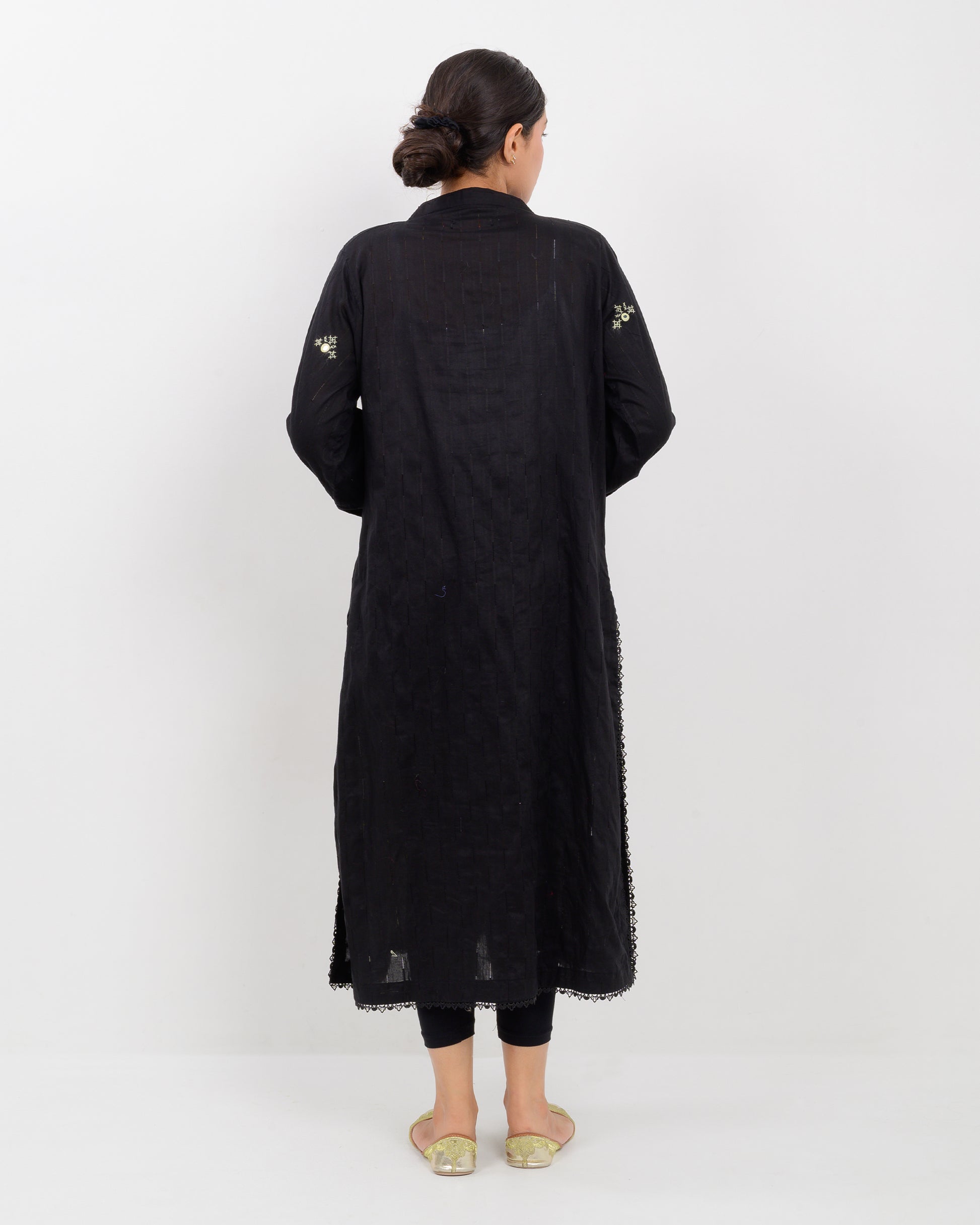 Woman wearing a black balochi embroidered kurta shirt with yellow patterns on a white background