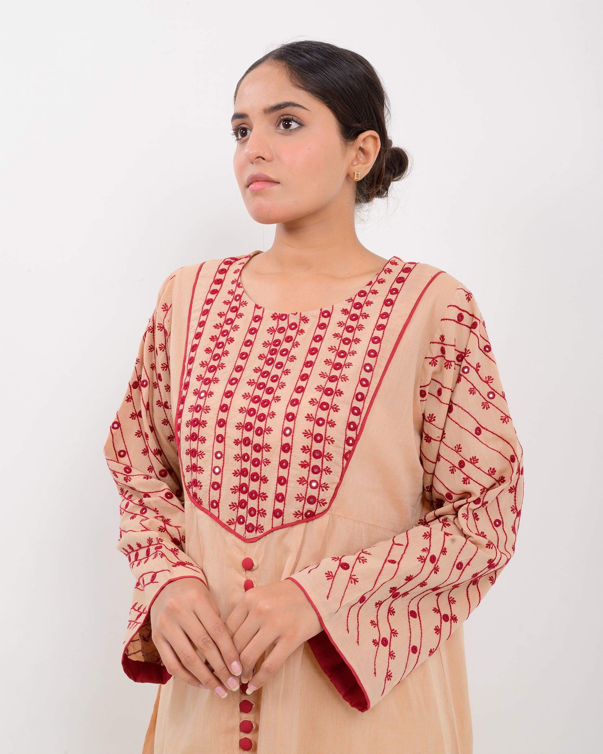 Woman wearing a peach color kachi sui embroidery long shirt on a white background