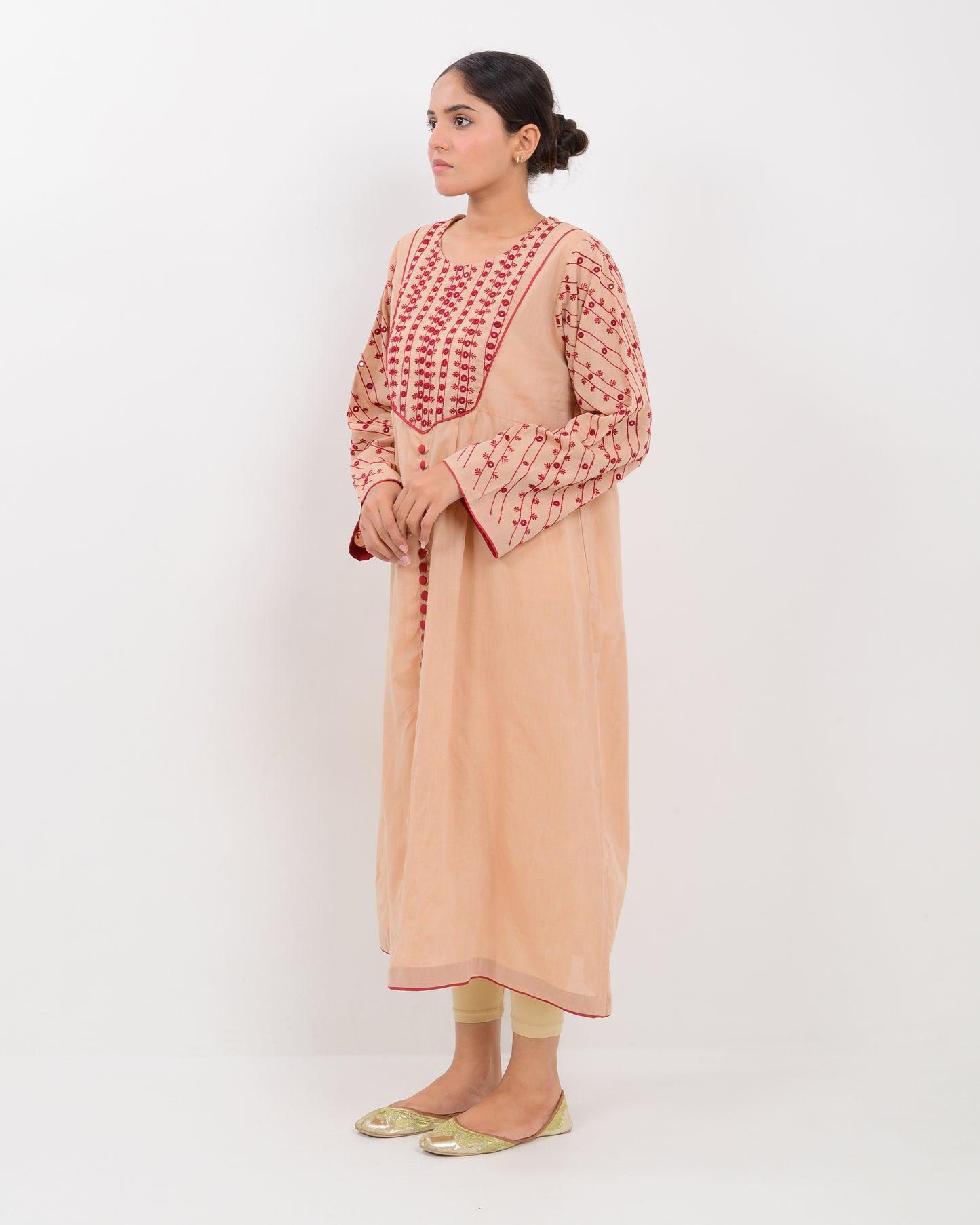 Woman wearing a peach color kachi sui embroidery long shirt on a white background