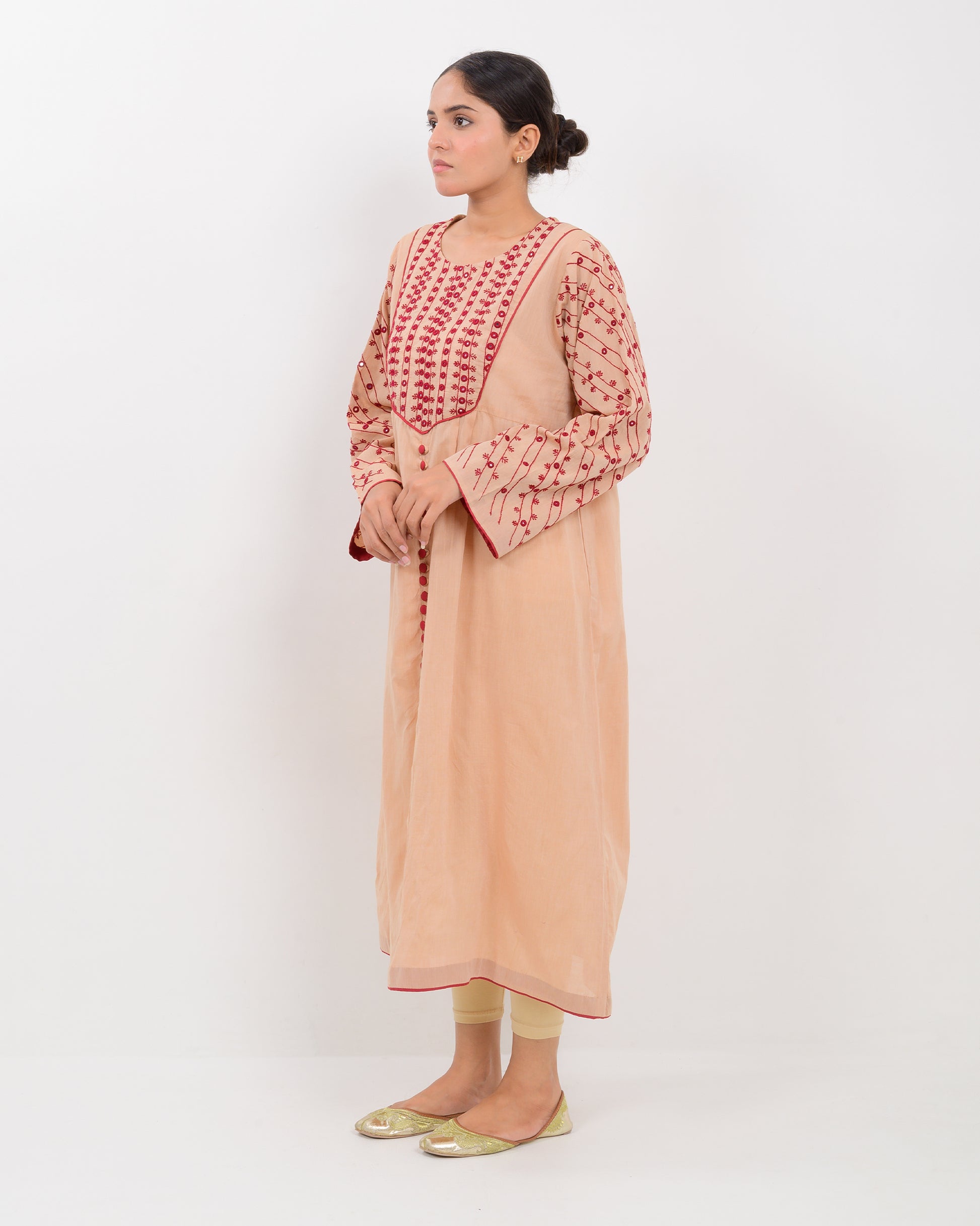 Woman wearing a peach color kachi sui embroidery long shirt on a white background