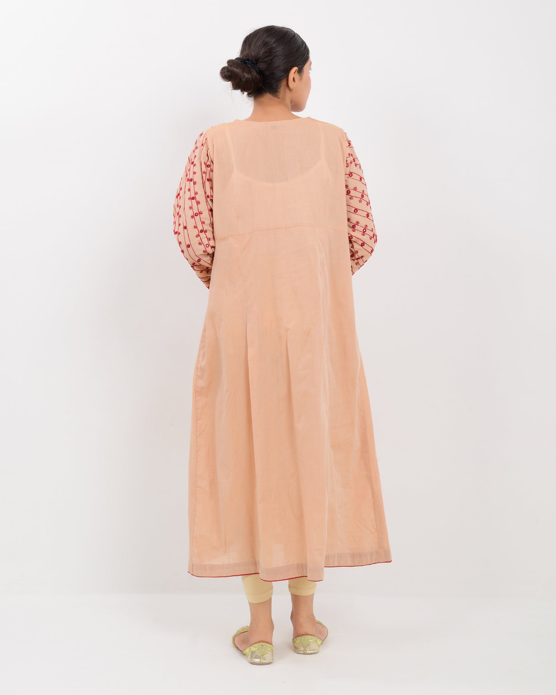 Woman wearing a peach color kachi sui embroidery long shirt on a white background