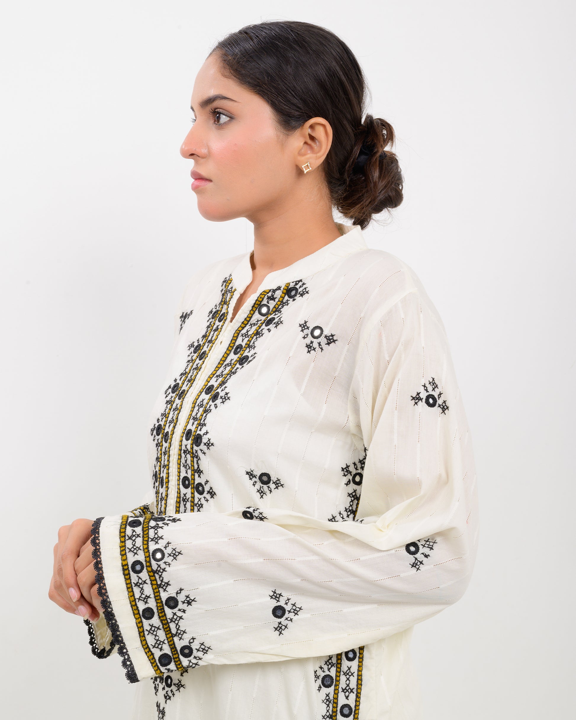 Woman wearing a white balochi embroidered kurta shirt with black patterns on a white background