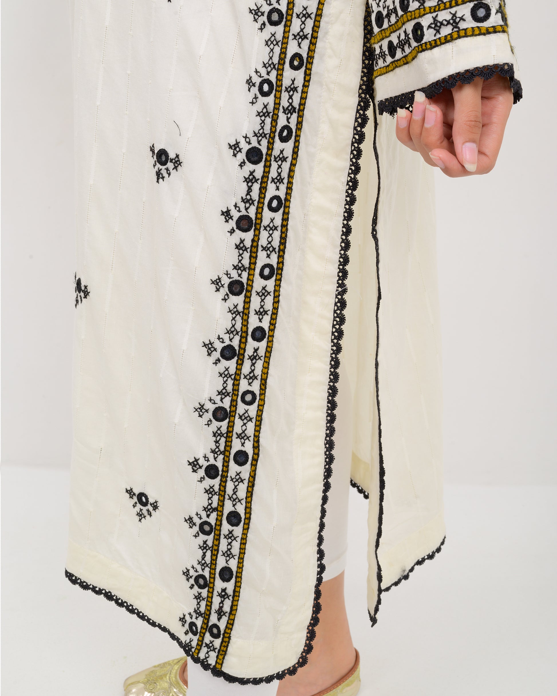 Woman wearing a white balochi embroidered kurta shirt with black patterns on a white background