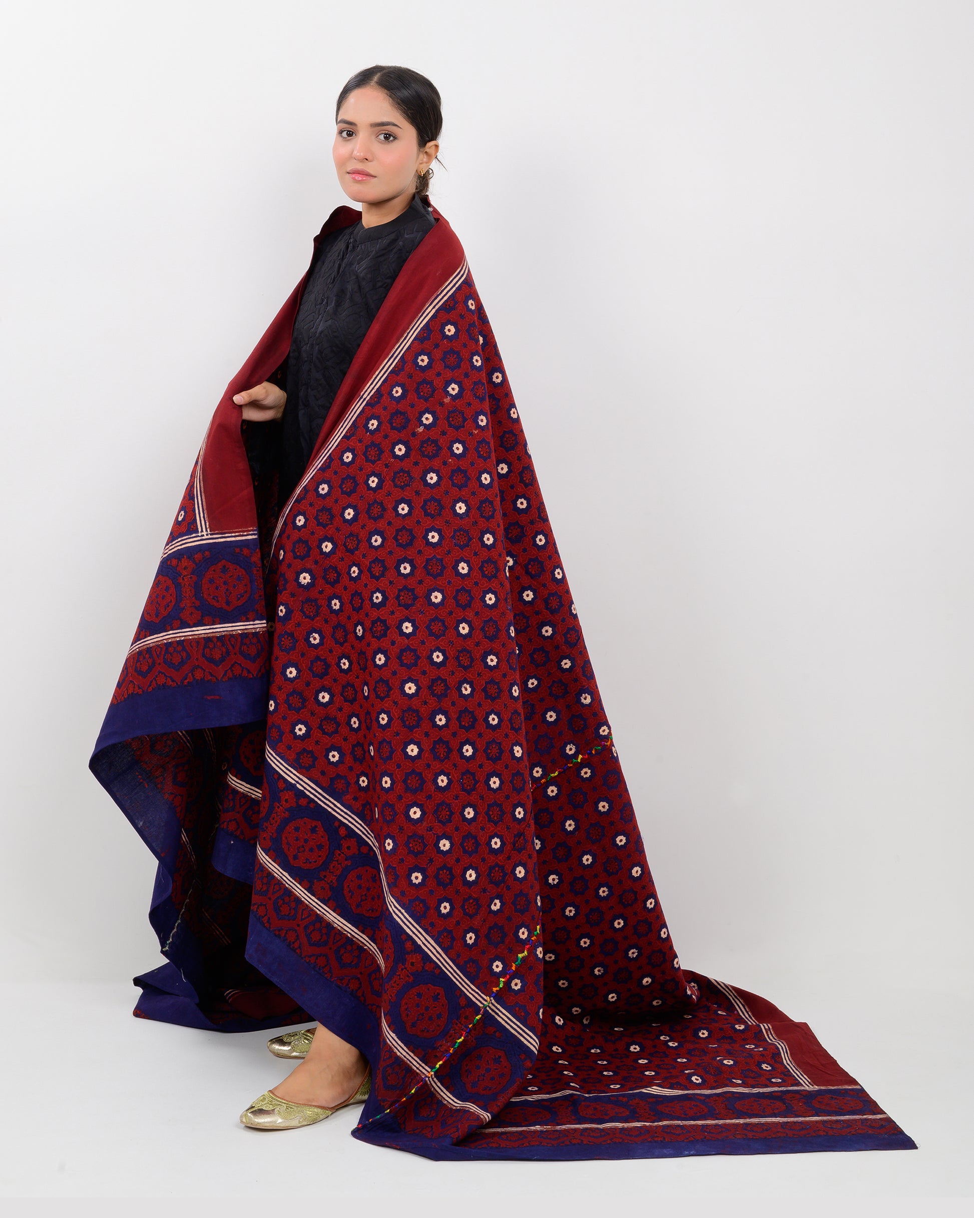 Woman holding a Sindhi traditional block print ajrak shawl against a white background