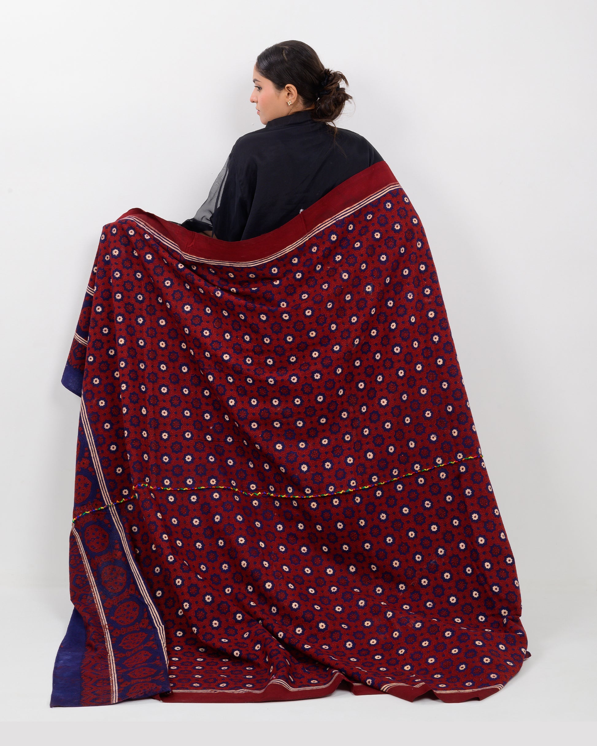 Woman holding a Sindhi traditional block print ajrak shawl against a white background