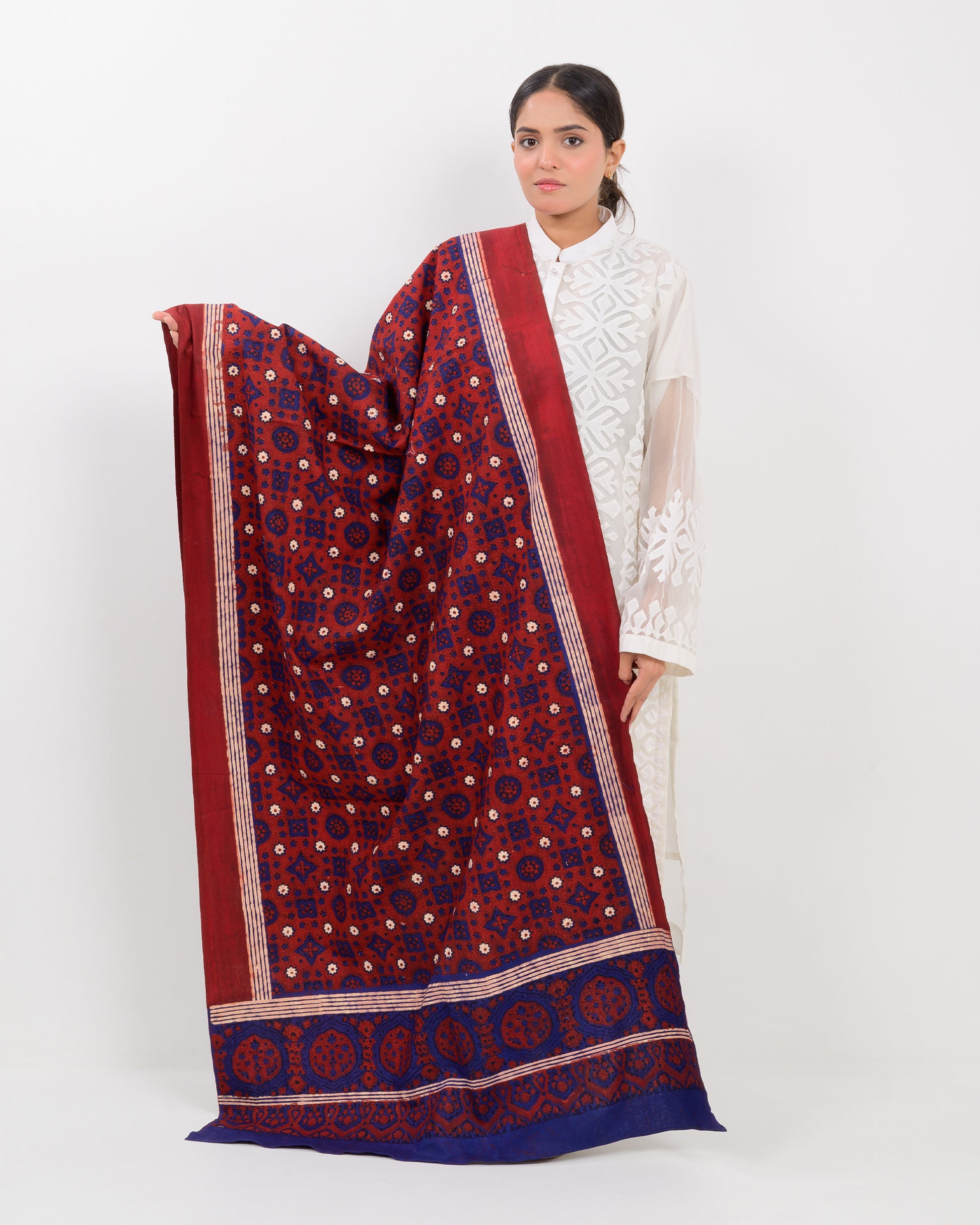 Woman holding a Sindhi traditional block print ajrak shawl against a white background
