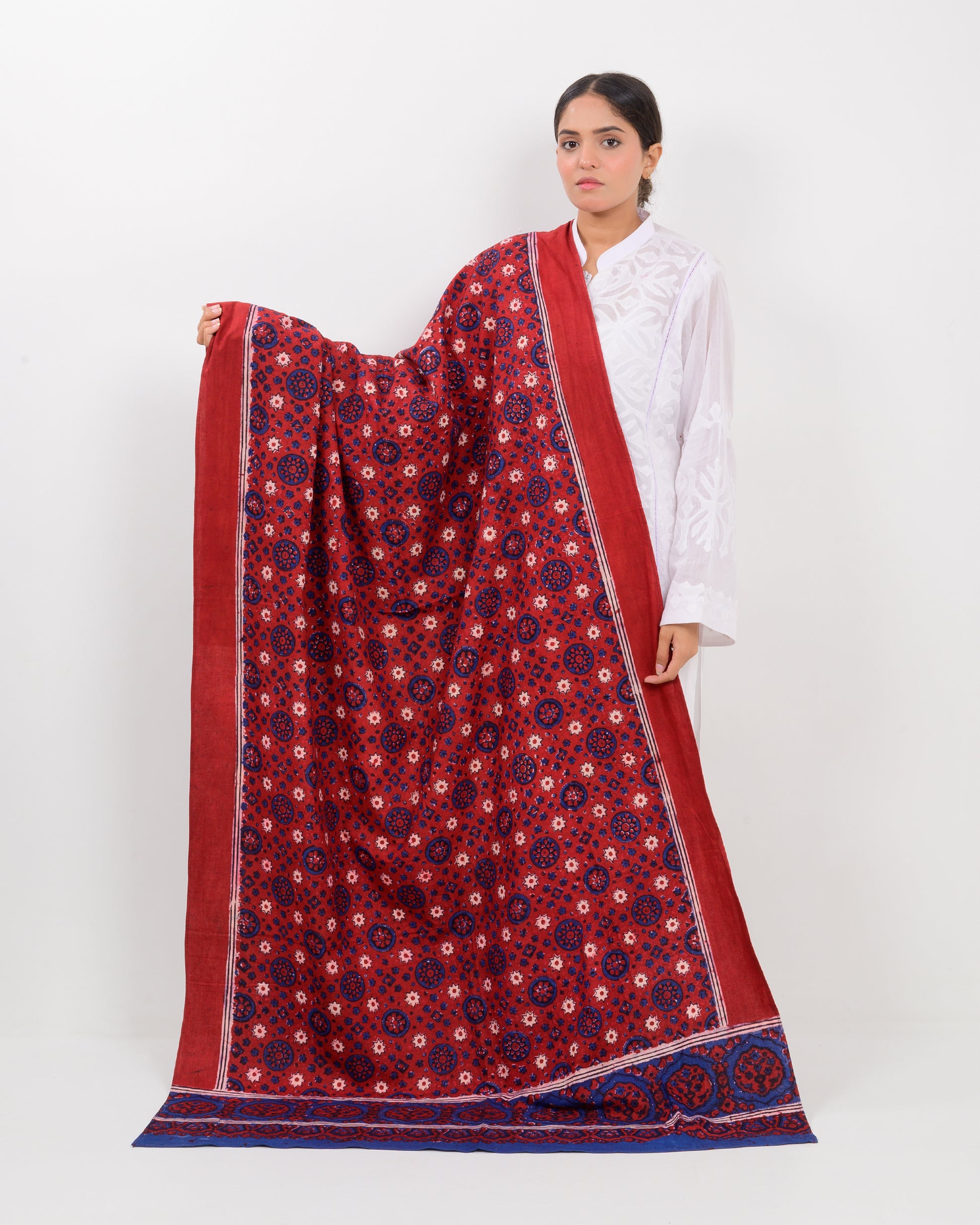 Woman holding a Sindhi traditional block print ajrak shawl against a white background