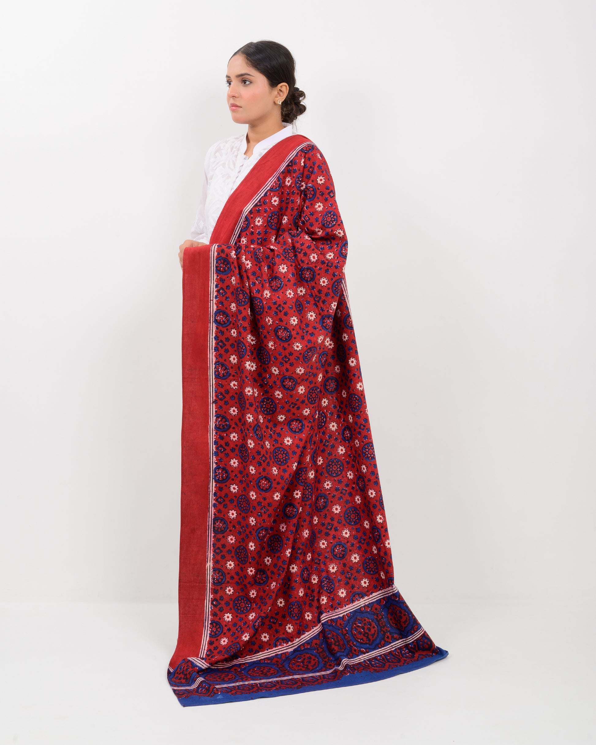 Woman holding a Sindhi traditional block print ajrak shawl against a white background