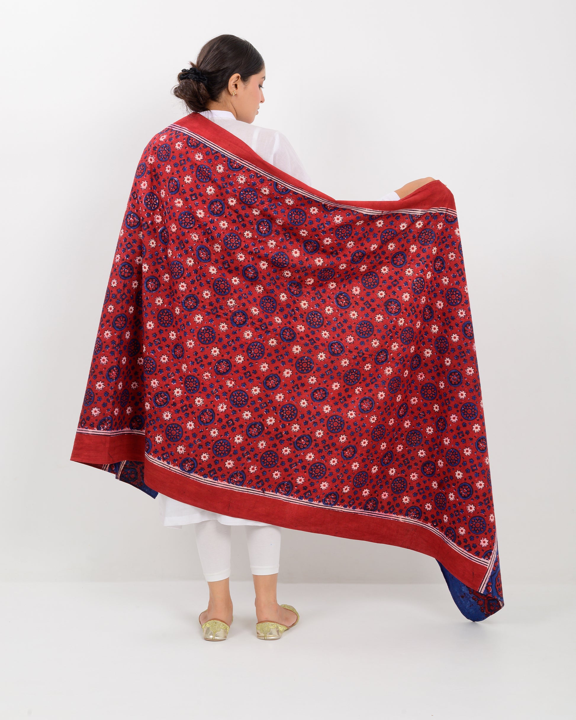 Woman holding a Sindhi traditional block print ajrak shawl against a white background