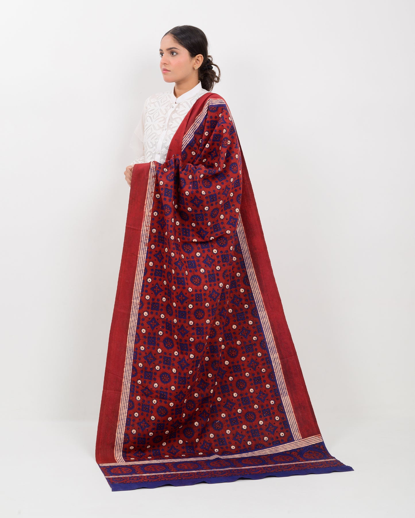 Woman holding a Sindhi traditional block print ajrak shawl against a white background
